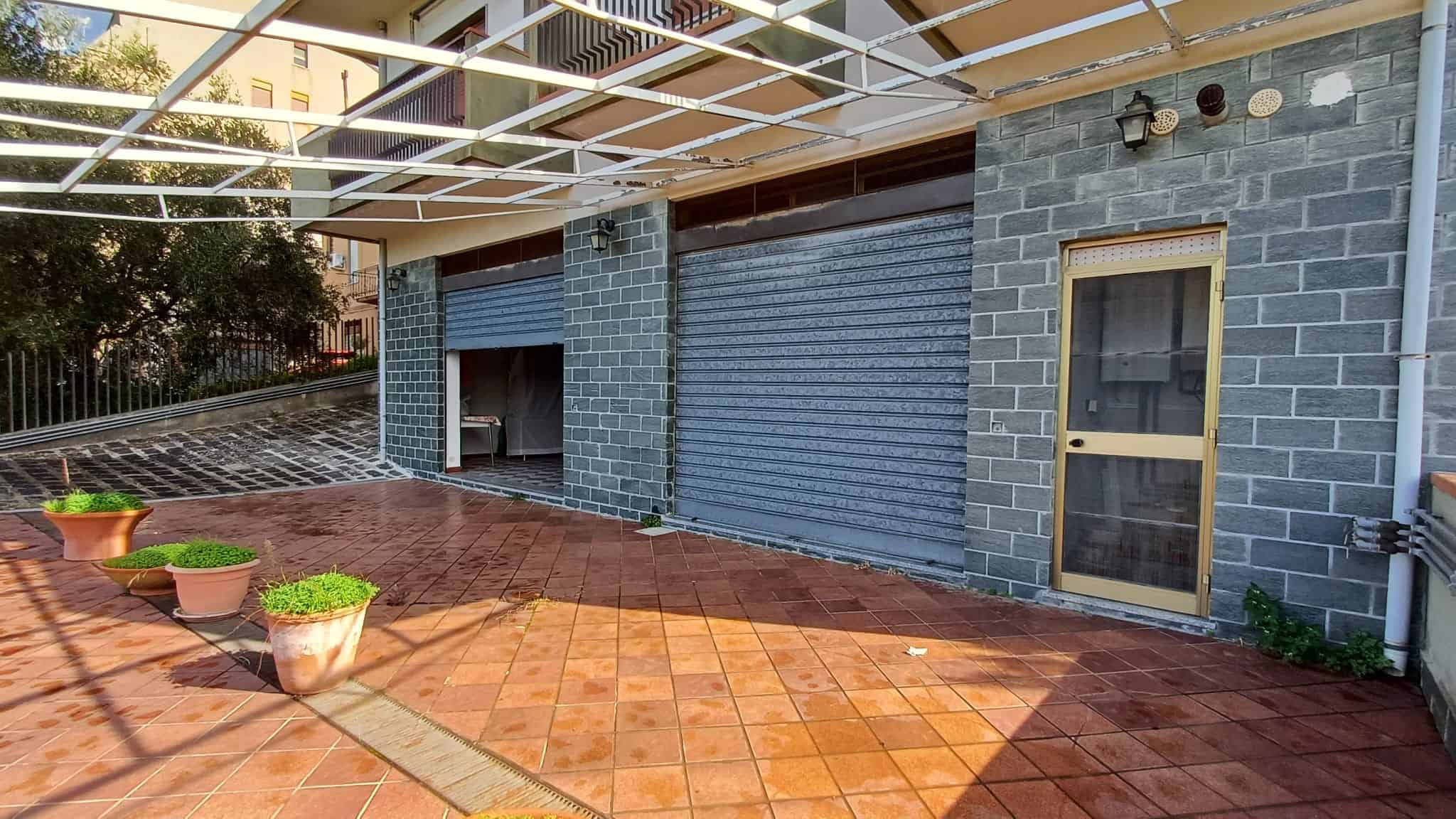 Finestra e portone di una casa in mattoni con grate di sicurezza e tapparelle, terrazza in gres rosso, arredamento esterno, illuminazione a parete, stile moderno, zona residenziale.