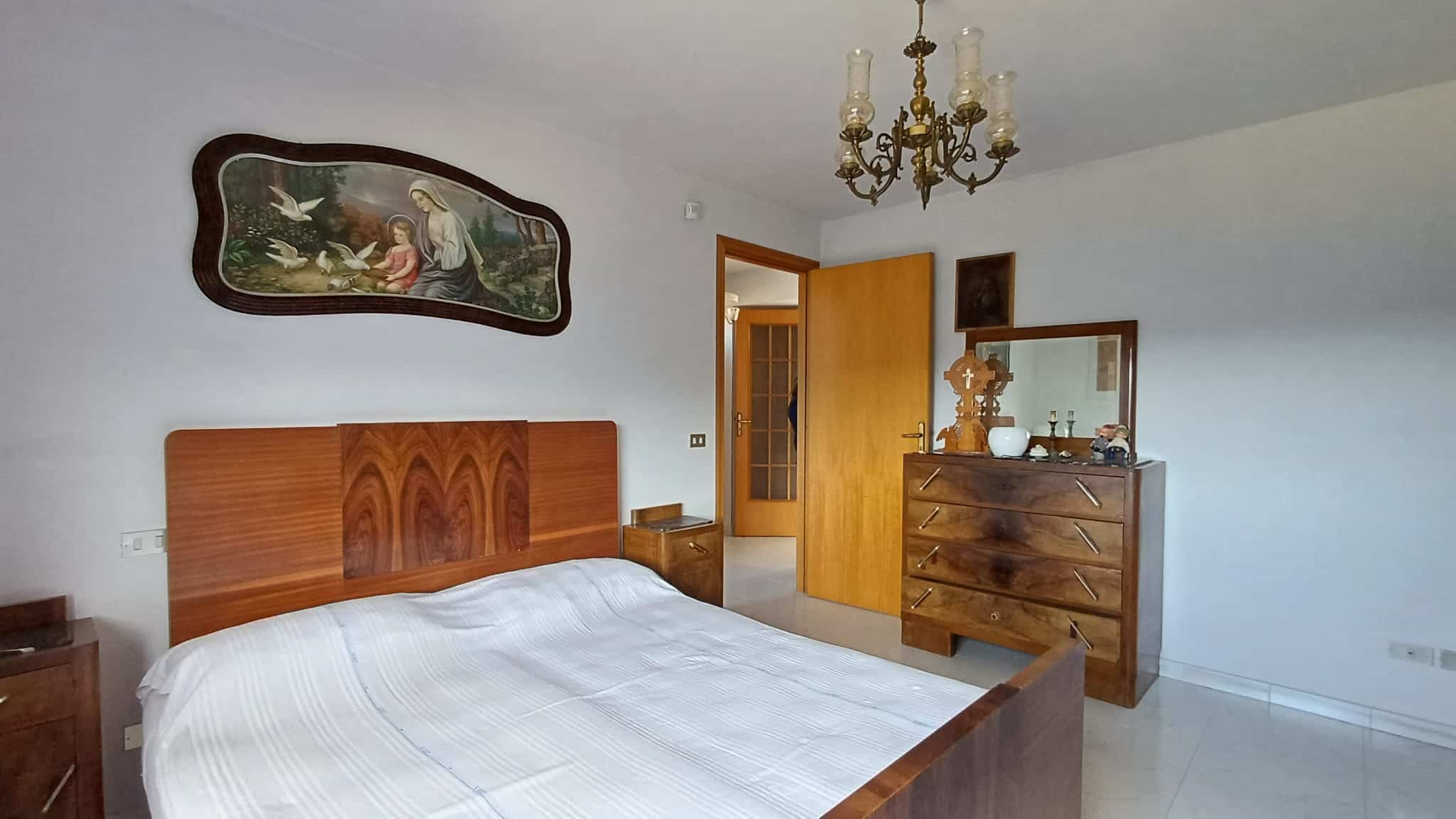 Letto matrimoniale con cabina armadio in camera da letto moderna, arredi in legno massello e decorazioni classiche, elementi d'arredo eleganti e funzionali.
