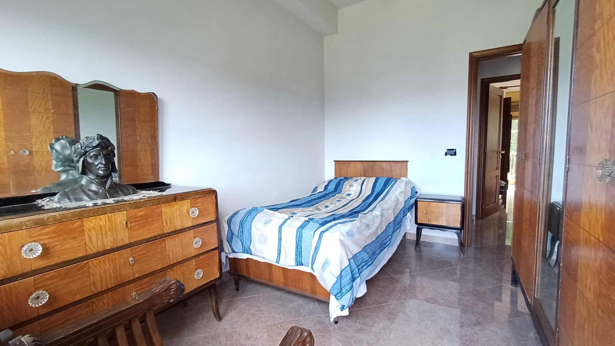 Stanza da letto spaziosa con mobili in legno di stile classico e decorazioni vintage, ideale per accoglienti soggiorni domestici e investimenti immobiliari di qualità.