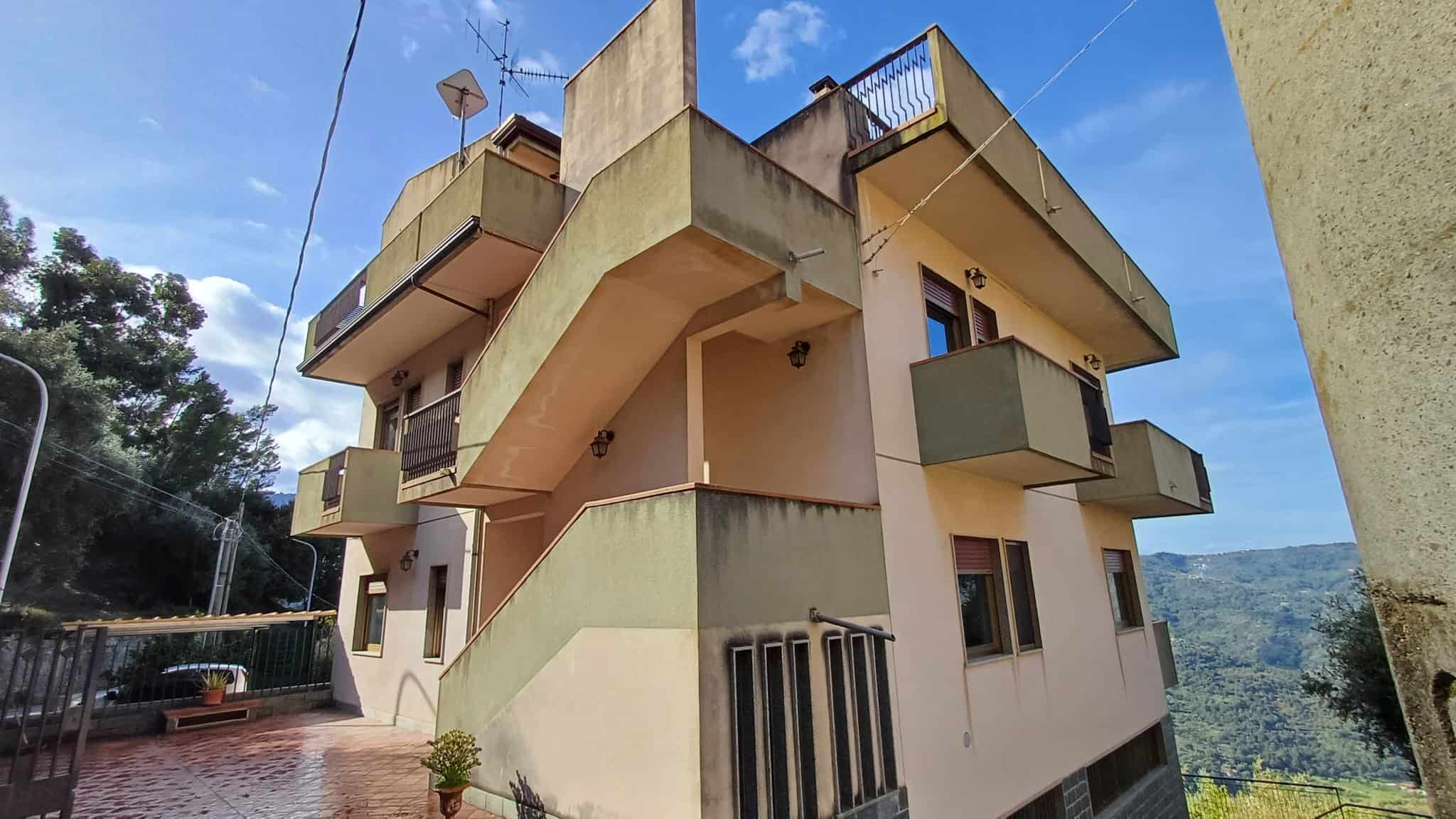 Interruttori di terrazza con vista panoramica su montagne e natura. Palazzo con balconi e pareti colorate in zona residenziale, immersa nel verde, con cielo sereno e clima gradevole.