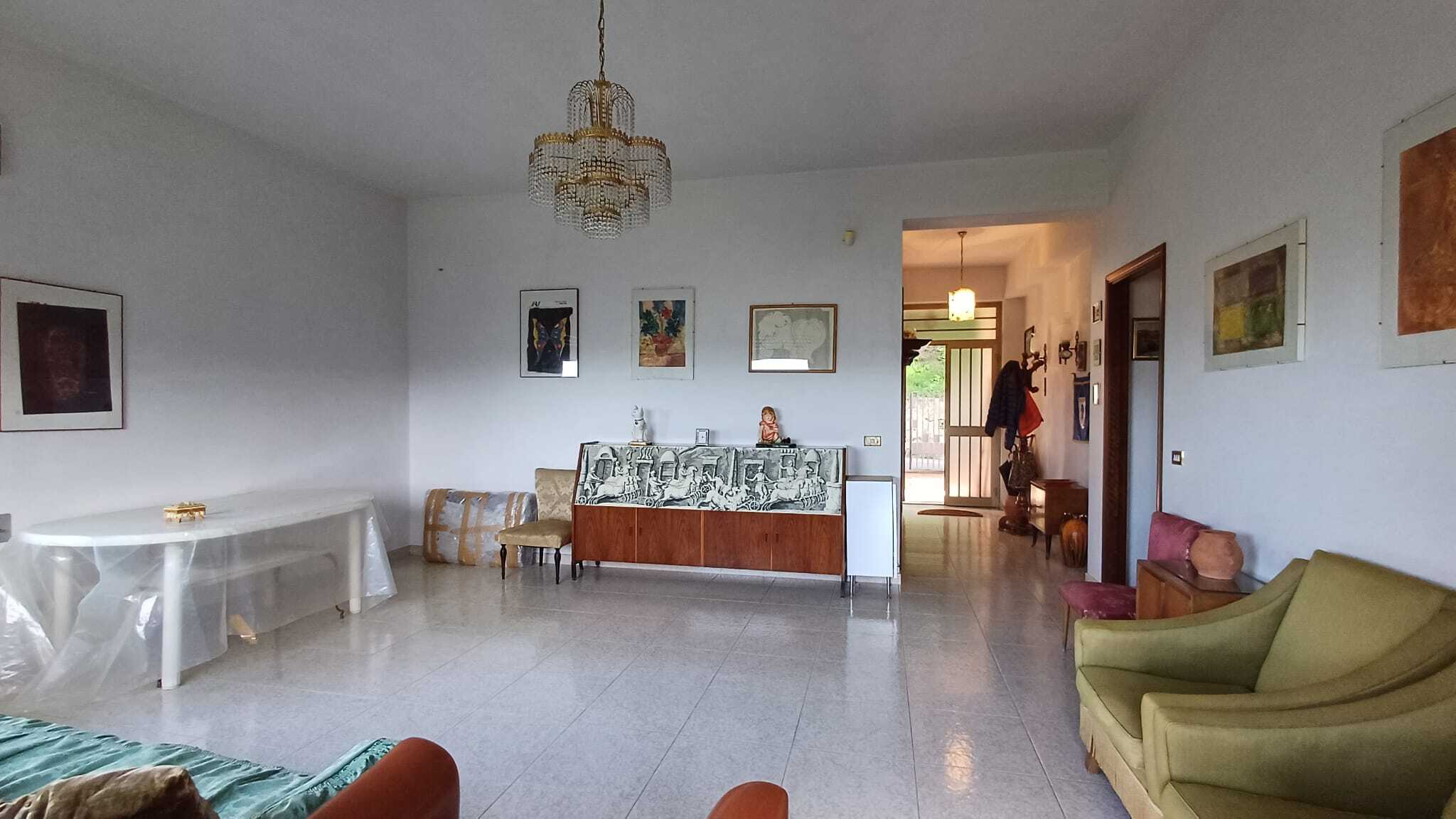 Ampio soggiorno con arredi vintage, divani colorati, lampadario a cristalli e decorazioni artistiche, ideale per trovare la casa perfetta con NextCasa.