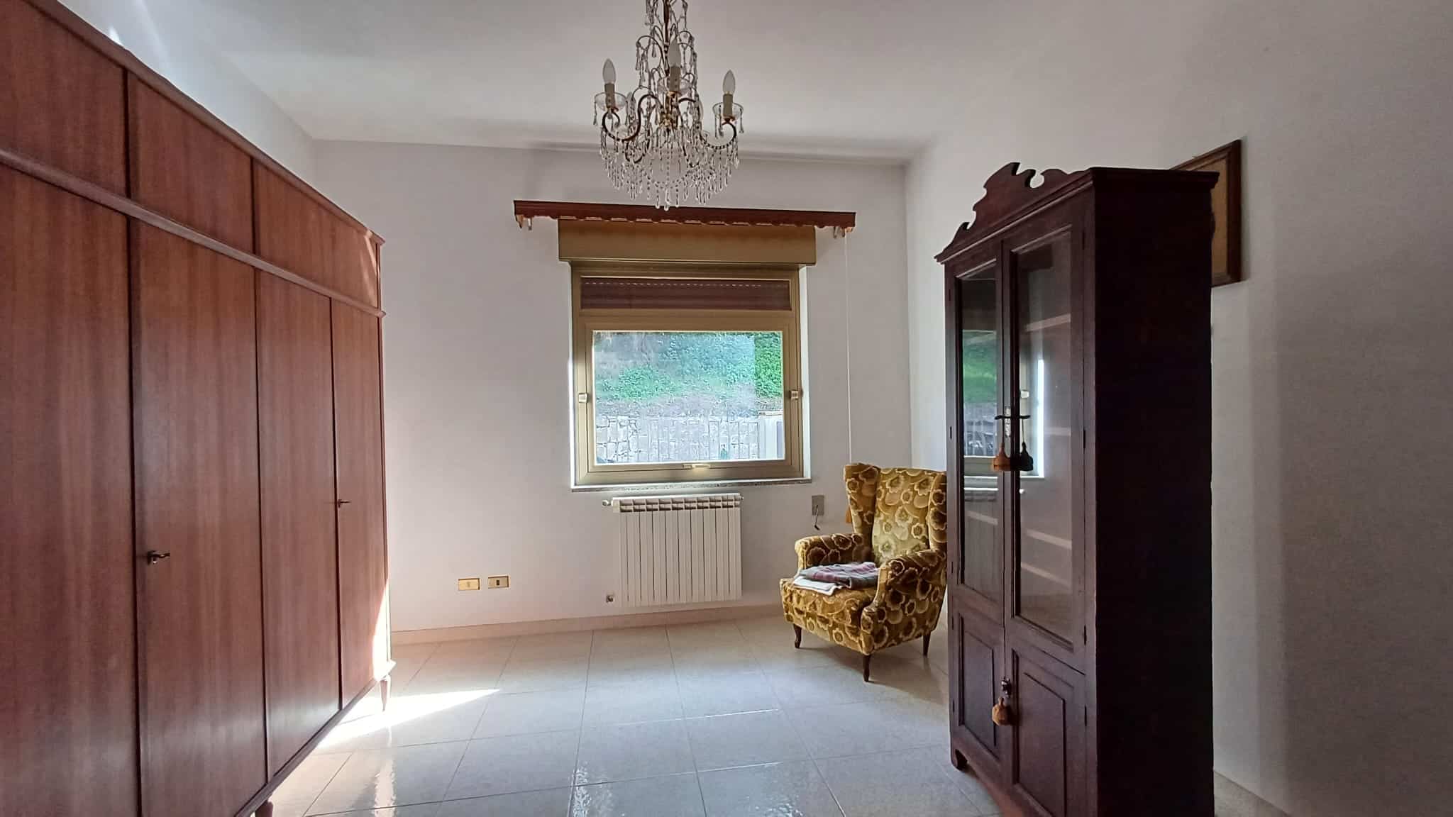 Armadio in legno e sedia classica in stile vintage in una stanza luminosa con finestra e chandelier.