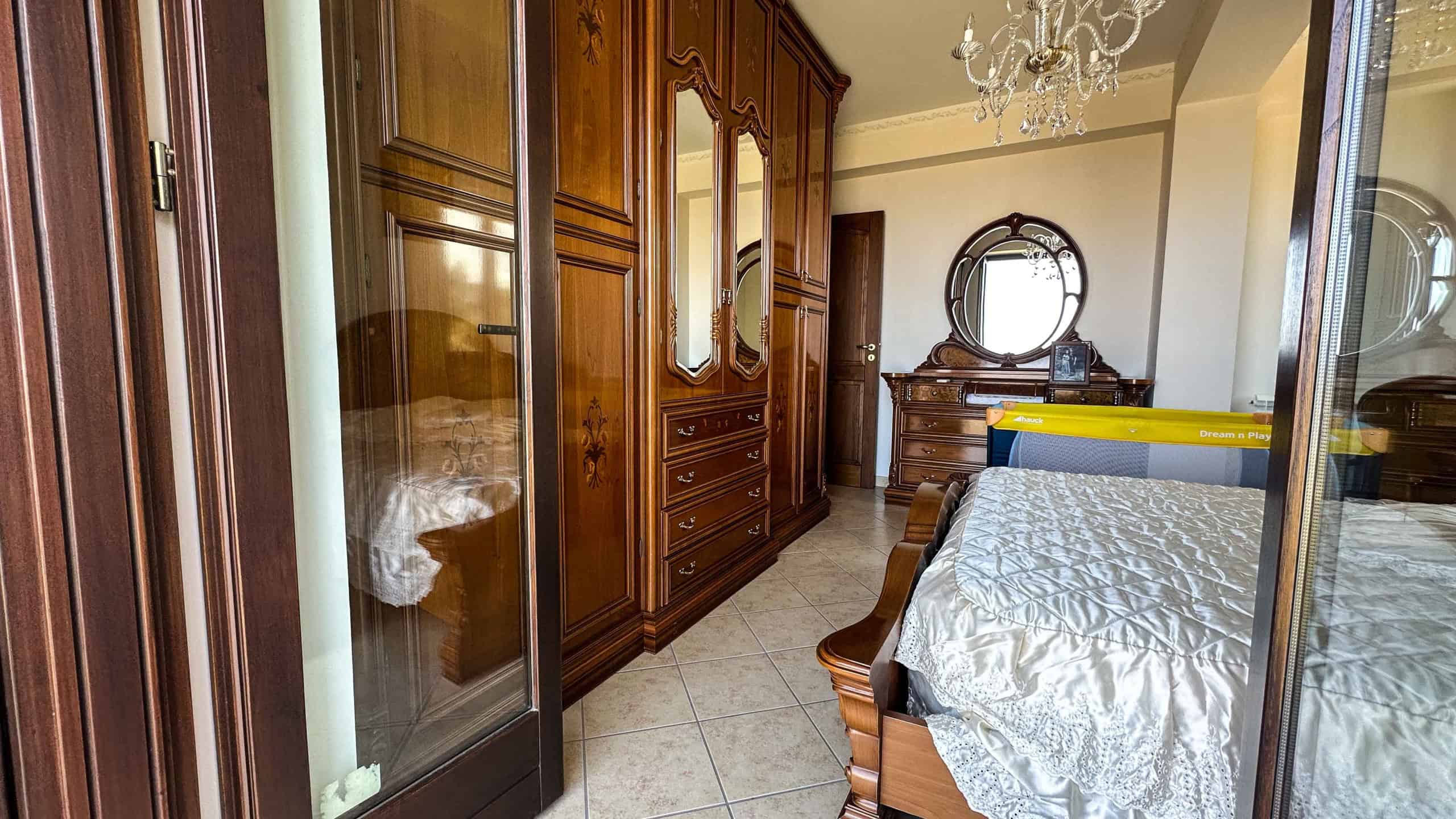 Armadio in legno massello con ante a specchio e dettagli lavorati, arredamento classico e raffinato in una camera da letto spaziosa.