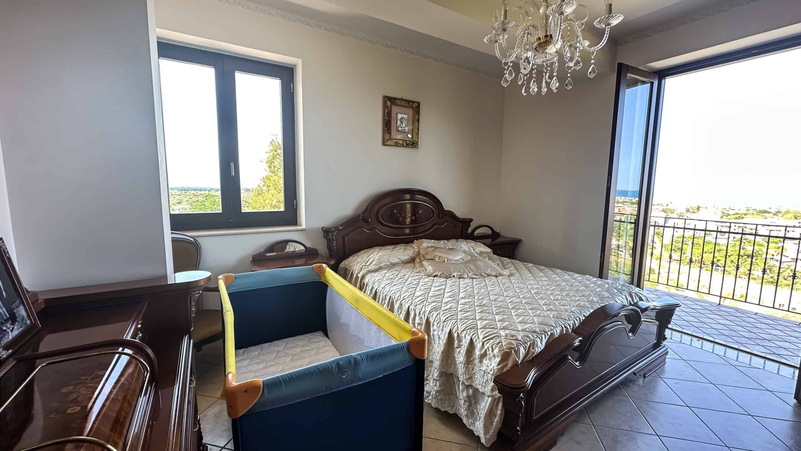 Letto matrimoniale con balcone vista panoramica, stile classico, camera da letto elegante, aria luminosa, arredamento contemporaneo, casa NextCasa, immobili di prestigio, appartamento di lusso, vista città, camera spaziosa, comfort abitativo.