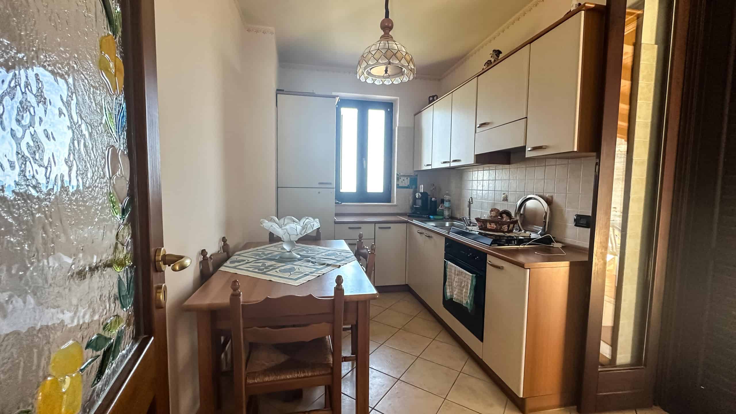 Spazio cucina abitabile con finestre, arredi in legno chiaro, elettrodomestici, tavolo da pranzo, atmosfera accogliente e luminosa, ideale per la vita quotidiana e momenti di convivialità.