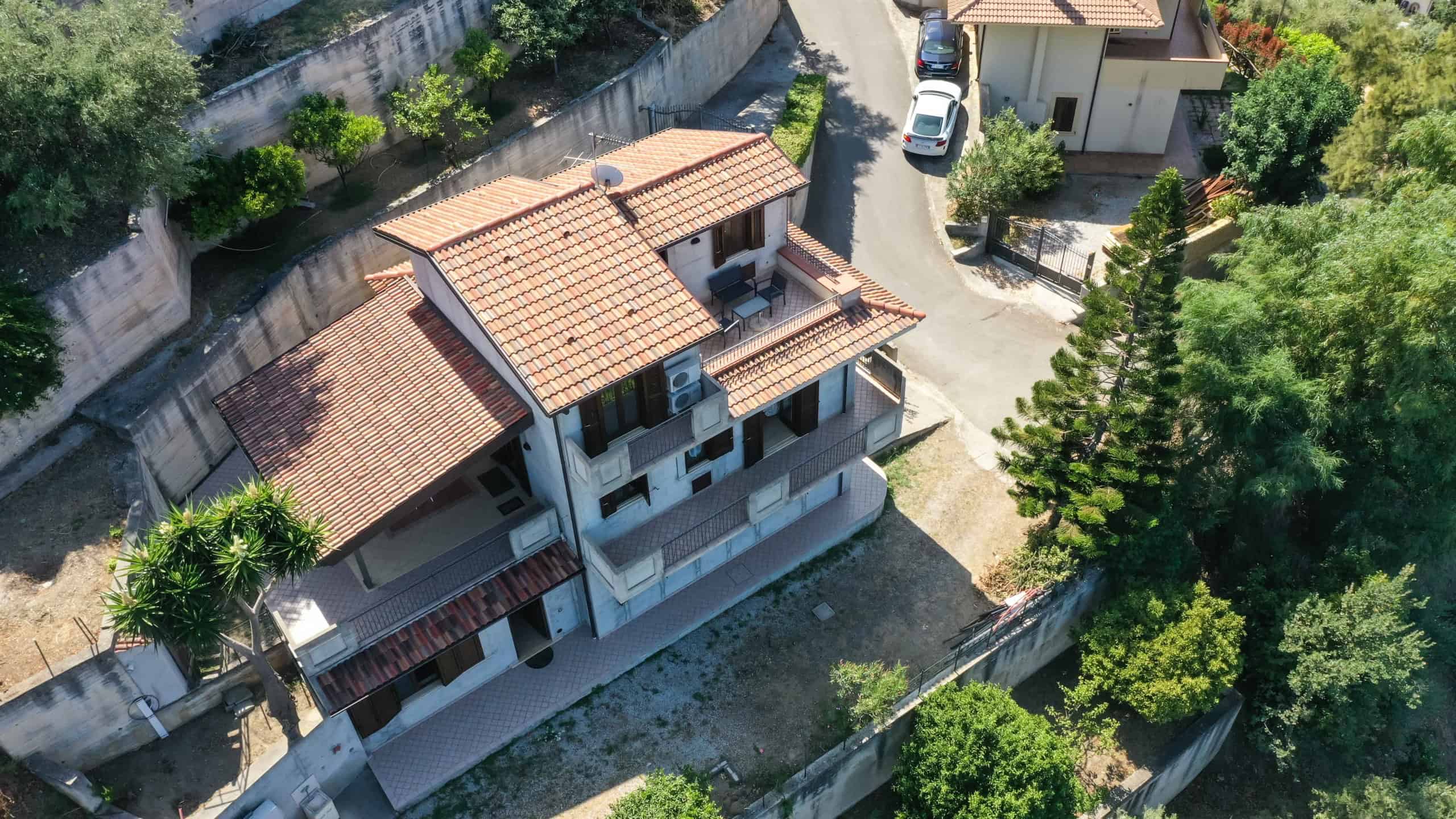 Casa bifamiliare con terrazza e giardino, vista aerea, zona residenziale verde, stile italiano, infissi moderni, ampie balconate, ambiente luminoso, contesto tranquillo, costruzione moderna, NextCasa.