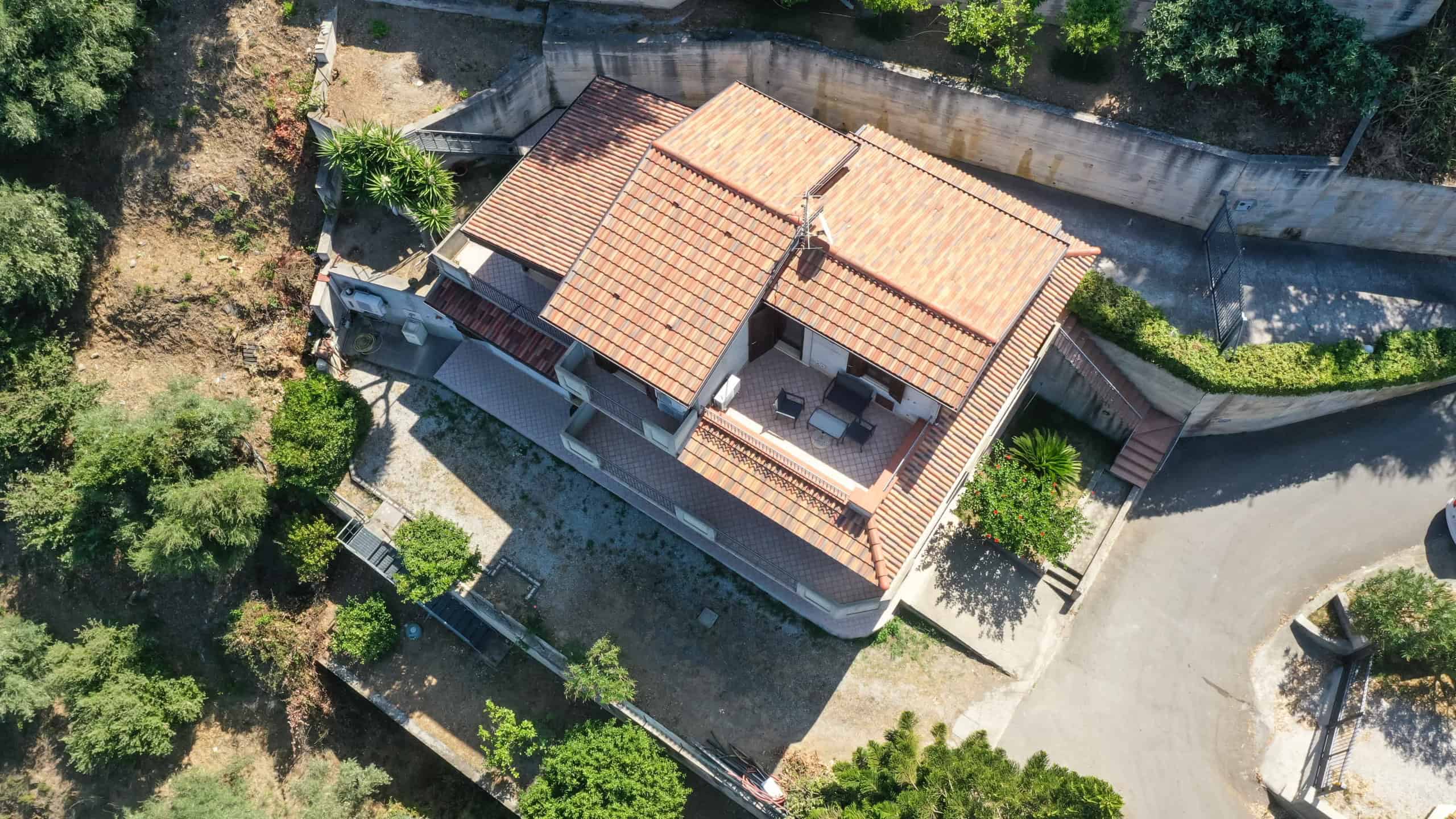 Tetto in terracotta e terrazza di una villa privata, vista aerea con giardino e spazio esterno, contesto residenziale tranquillo, immobiliare NextCasa.