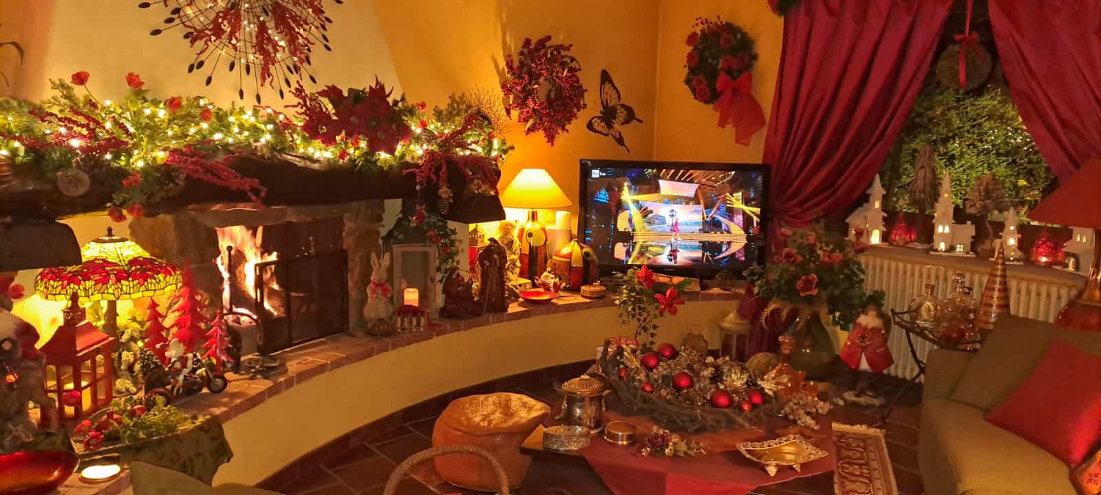 Accogliente soggiorno natalizio con caminetto decorato con luci e ornamenti rossi, ambiente caldo e festoso, perfetto per le festività.