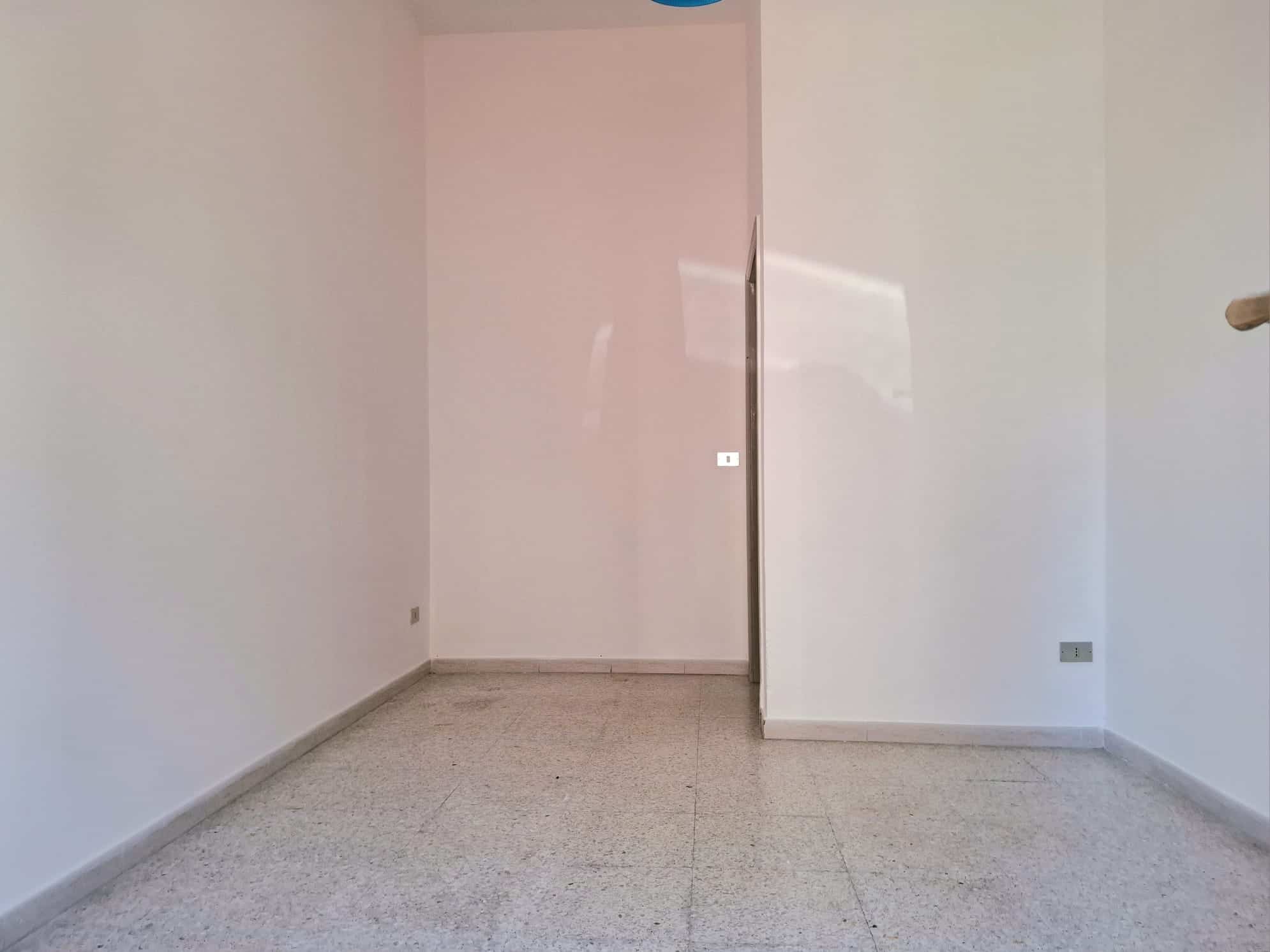 Lavagna vuota in una stanza moderna con pareti bianche e pavimento in piastrelle chiare, pronta per arredamento o personalizzazione.