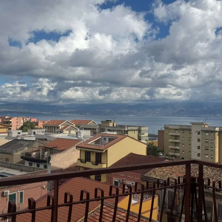 Ambiente urbano con vista sul mare e sul cielo nuvoloso, mostrando edifici residenziali e un mare calmo sullo sfondo, ideale per immagini di immobili con vista panoramica e location in riva al mare.