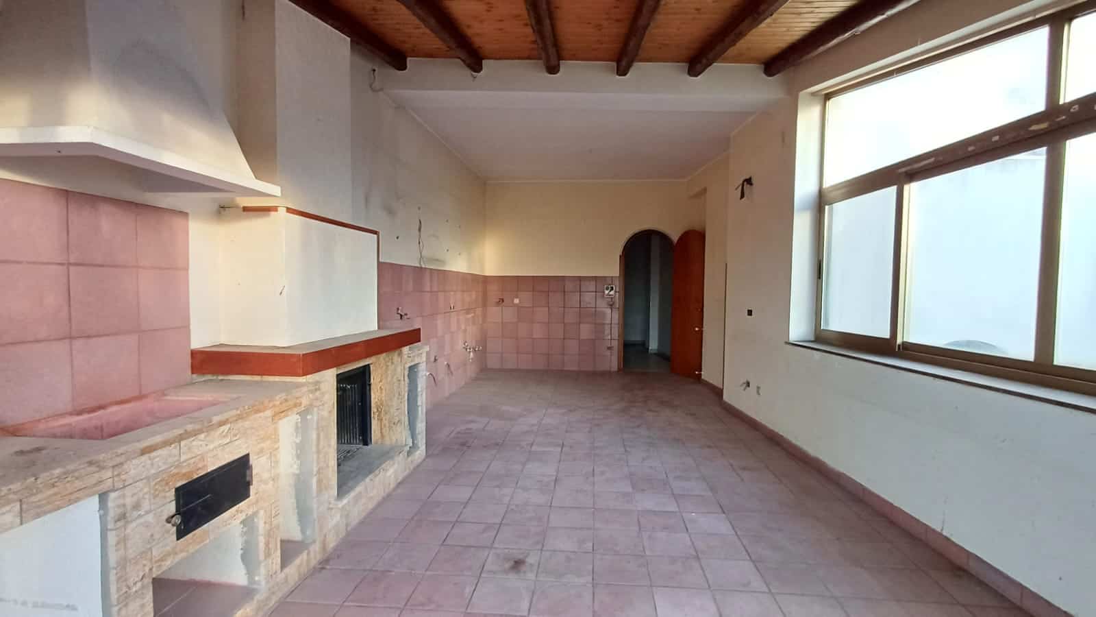 Ampio soggiorno con camino in stile rustico, pareti luminose e grandi finestre, ideale per ristrutturare e valorizzare la tua casa. Perfetto per progetti di interior design e ristrutturazioni edilizie.