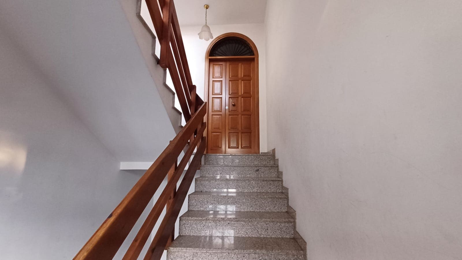 Crepa d'ingresso in legno, scale in marmo, arredamento casa elegante, porta in legno con arcata, ingresso casa moderna, ristrutturazione appartamento, soluzioni abitative, NextCasa, immobili di prestigio, design interno.