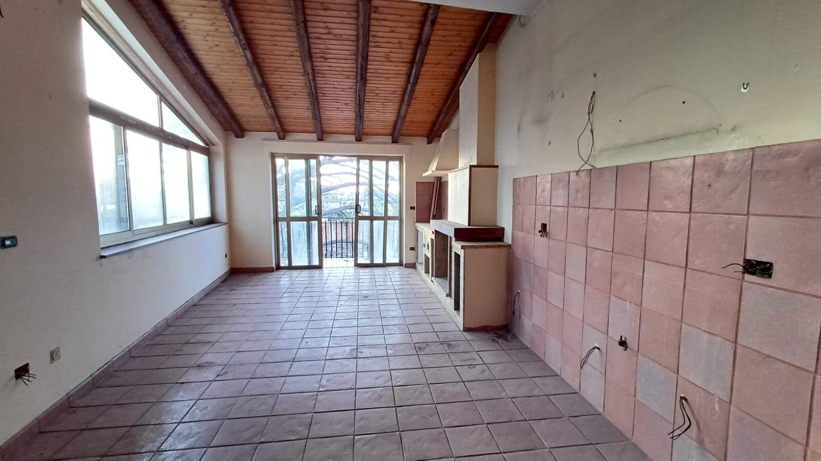 1. Ambiente da cucina in fase di ristrutturazione con grandi finestre, pareti neutre e tetto in legno a travi a vista, pronto per arredi e installazioni.