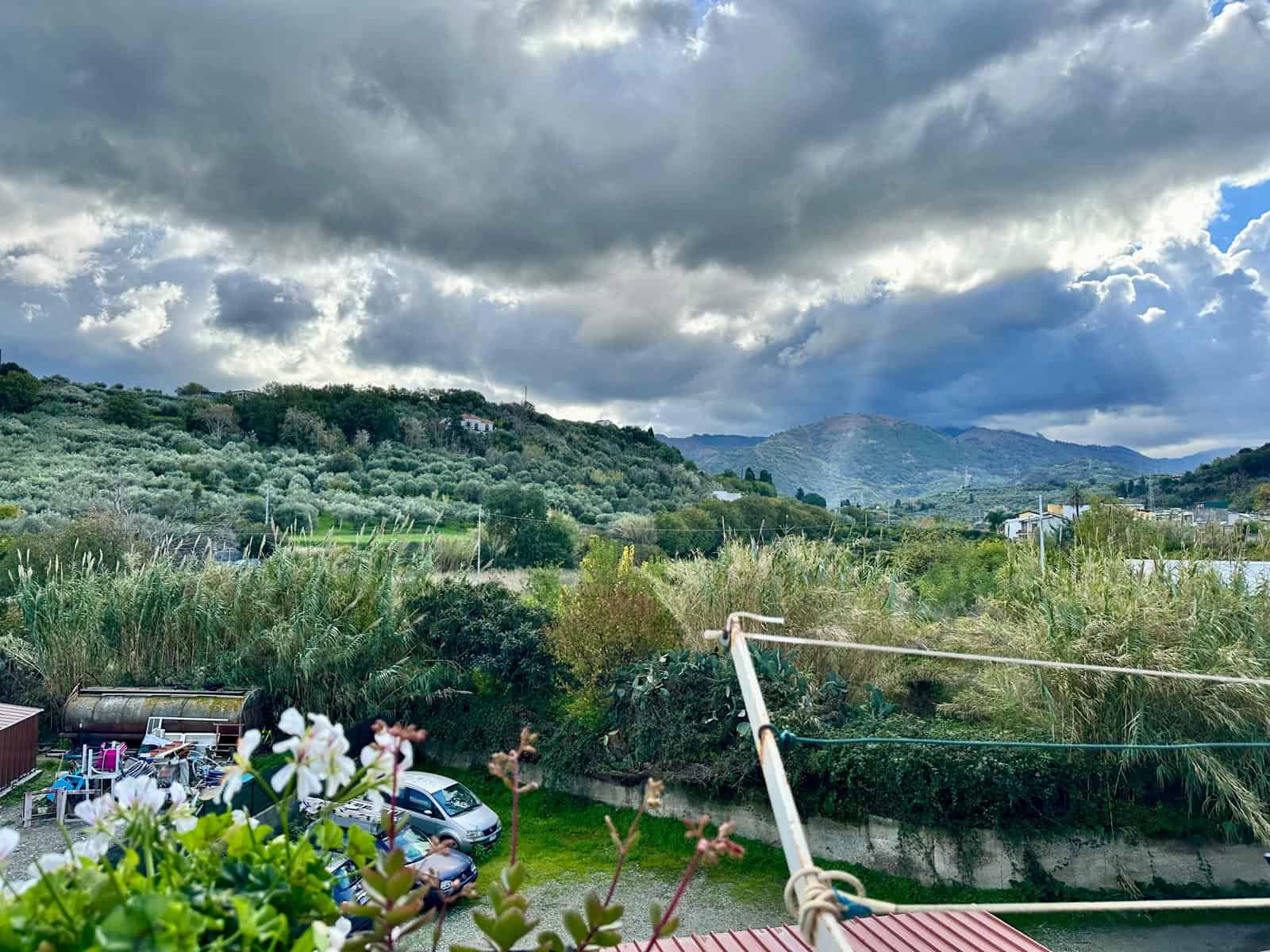 Vista panoramica sulle colline e il paesaggio naturale in Toscana, con nuvole in cielo, vegetazione verde e alcune case, perfetta per annunci immobiliari e promozione di immobili su NextCasa.