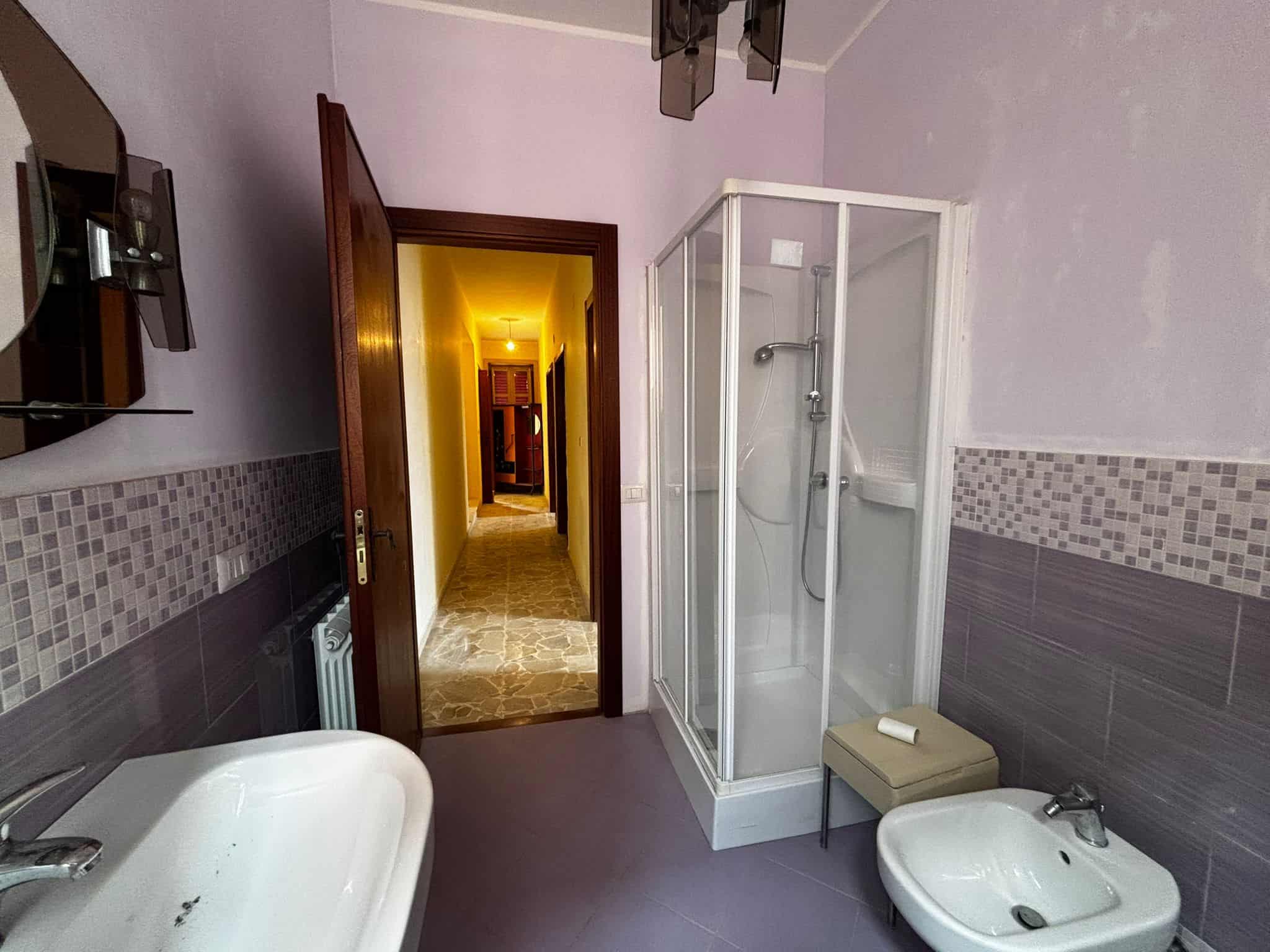 Doccia in bagno con piastrelle moderne, lavabo e bidet per comfort quotidiano, ambiente luminoso e funzionale ideale per sistemazioni residenziali o affitti brevi, vicino a corridoio e ingresso.