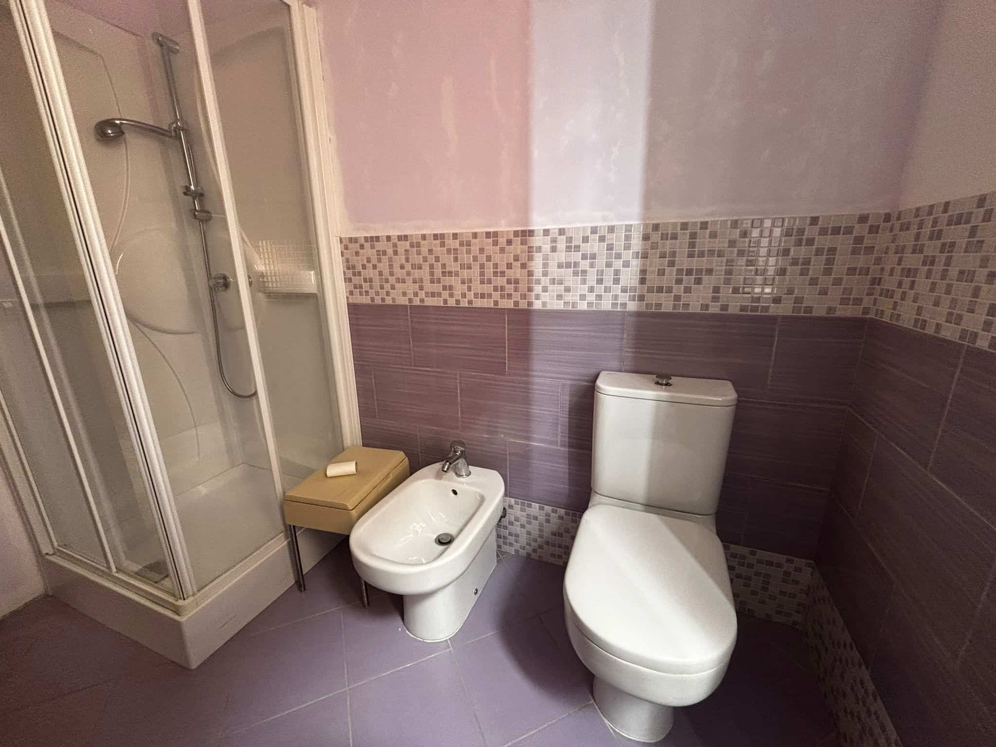 Scarico bagno con doccia, bidet e wc, rivestimenti murali in mosaico e piastrelle colorate, ambiente moderno e funzionale.