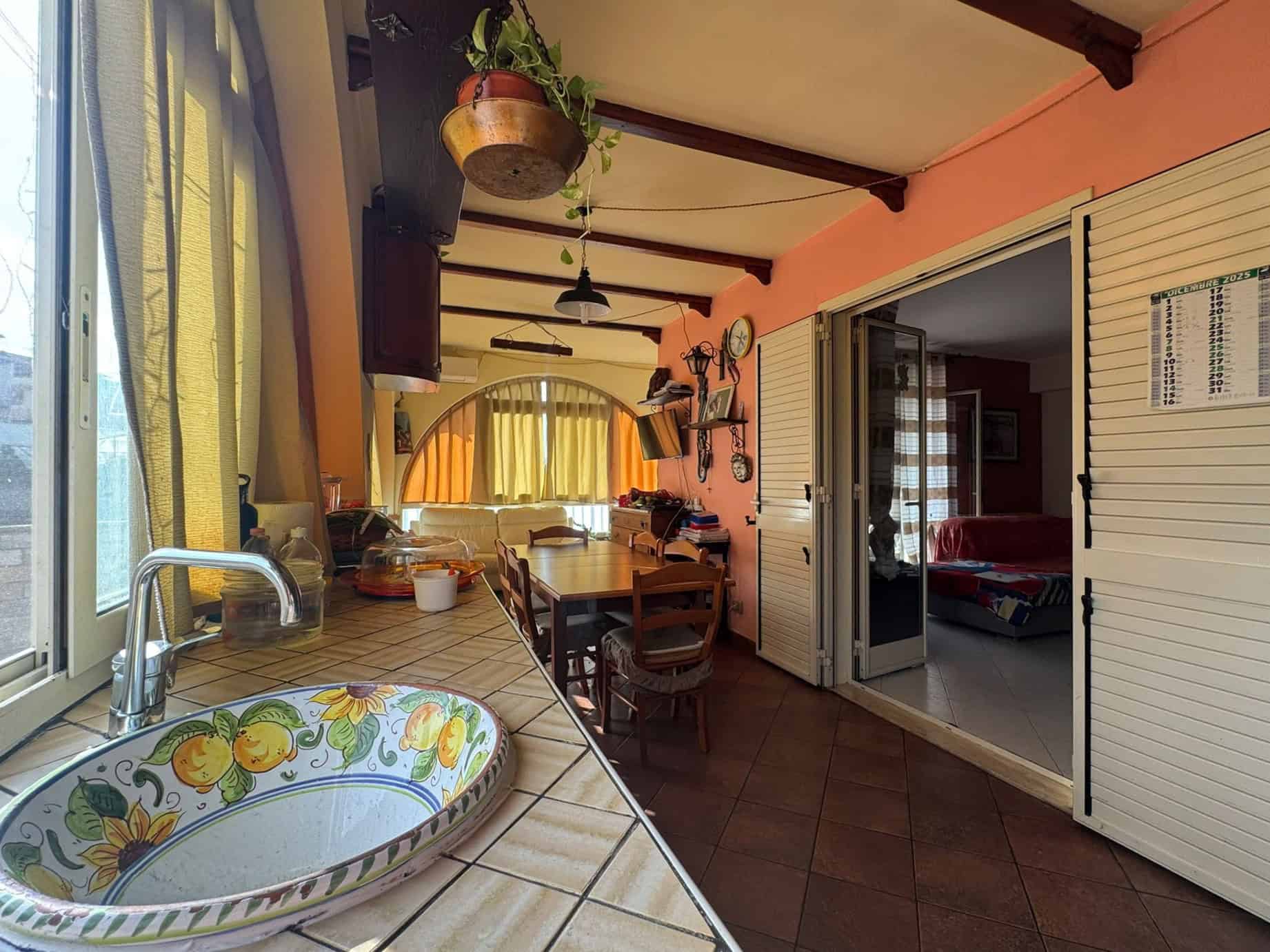 Lavanderia e zona pranzo luminosa con grande finestra, arredi caldi e dettagli colorati, ideale per vivere e cucinare in comfort, con accesso diretto a soggiorno e spazio funzionale in ambiente accogliente.