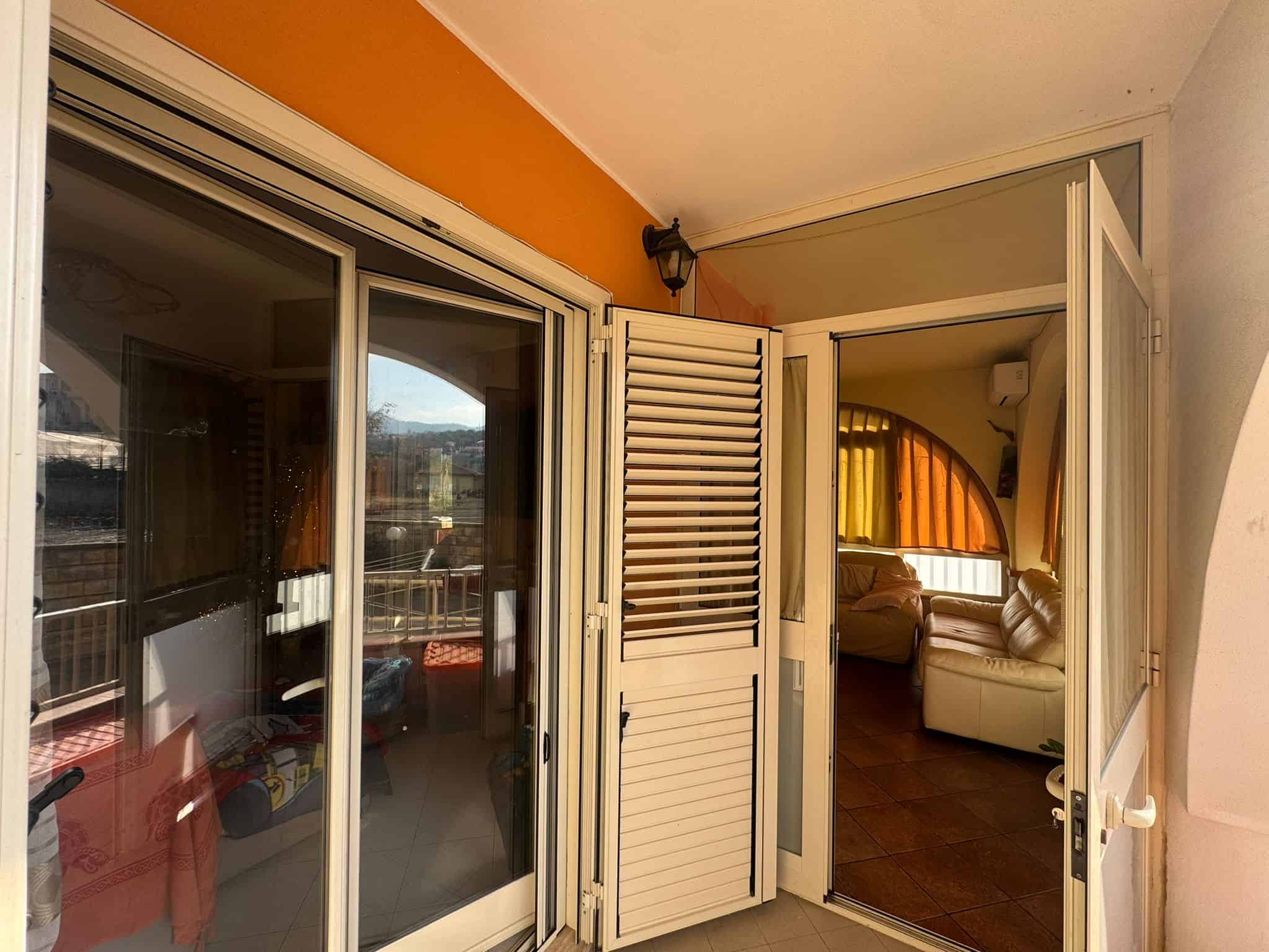 Vista balcone con porta scorrevole e finestra, living luminoso con divano, arredi moderni, ambienti accoglienti, ideale per affitti brevi e vendita immobili a Roma.