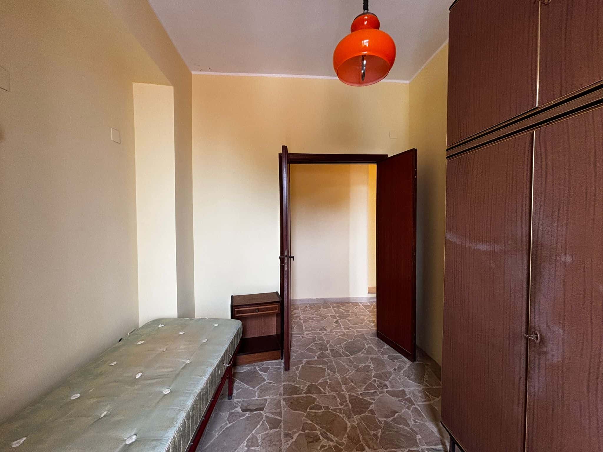 Armadio a muro in legno e stanza da letto con letto singolo e arredamento funzionale a NextCasa, soluzione abitativa comoda e pratica per affitti a breve o lungo termine.