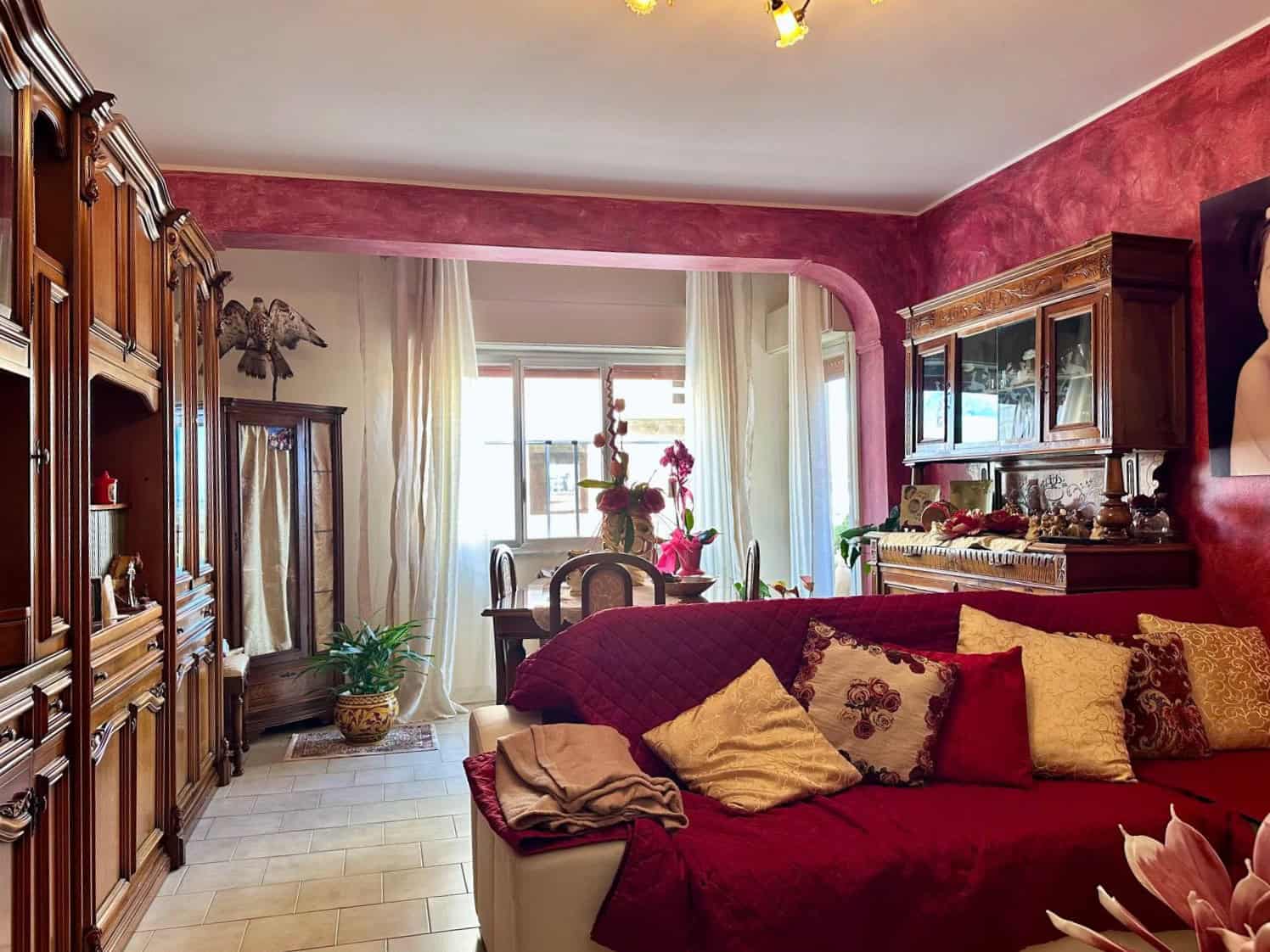 1. Salotto di eleganza con mobili in legno pregiato, divano rosso e decorazioni vintage, ambiente accogliente e raffinato.