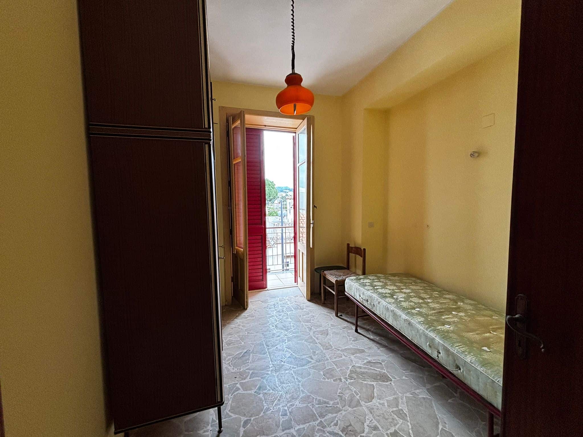 Stanza da letto con balcone, arredo semplice e pavimento in marmo, luminosa e accogliente, ideale per affitti turistici o residenziali, in zona tranquilla.