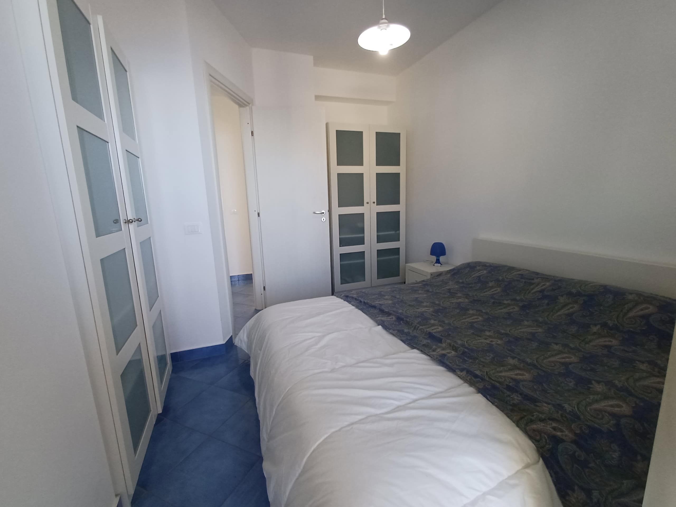 Appartamento moderno con camera da letto arredata, armadi a specchio, comò e lampada notturna, ideale per affitti turistici e residenziali, situato in zona tranquilla e ben servita.