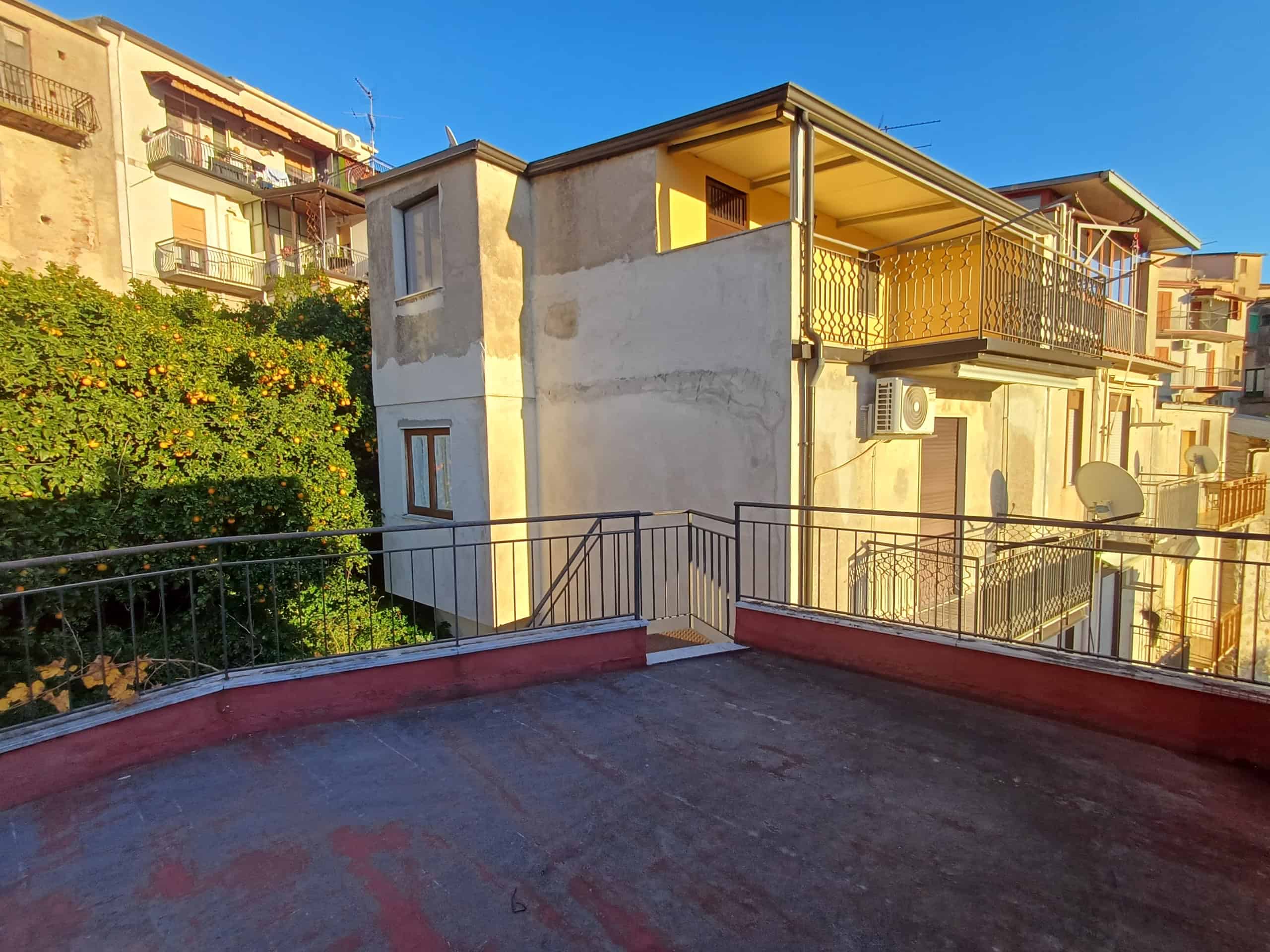 Vista panoramica di un appartamento con terrazza privata, edificio residenziale, aria condizionata e balconi solari, situato in zona urbanizzata vicino a servizi e spazi verdi, ideale per investimento immobiliare.