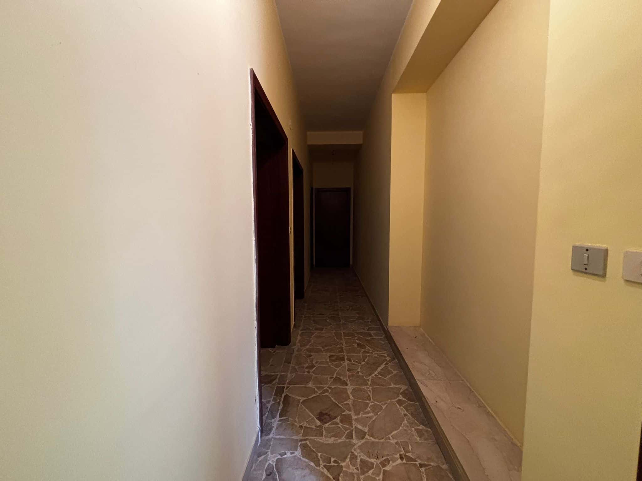 Spazi interni di un appartamento in affitto con pareti gialle e pavimento in marmo, vista su corridoio con porte in legno, ambiente luminoso e accogliente, servizi immobiliari NextCasa.