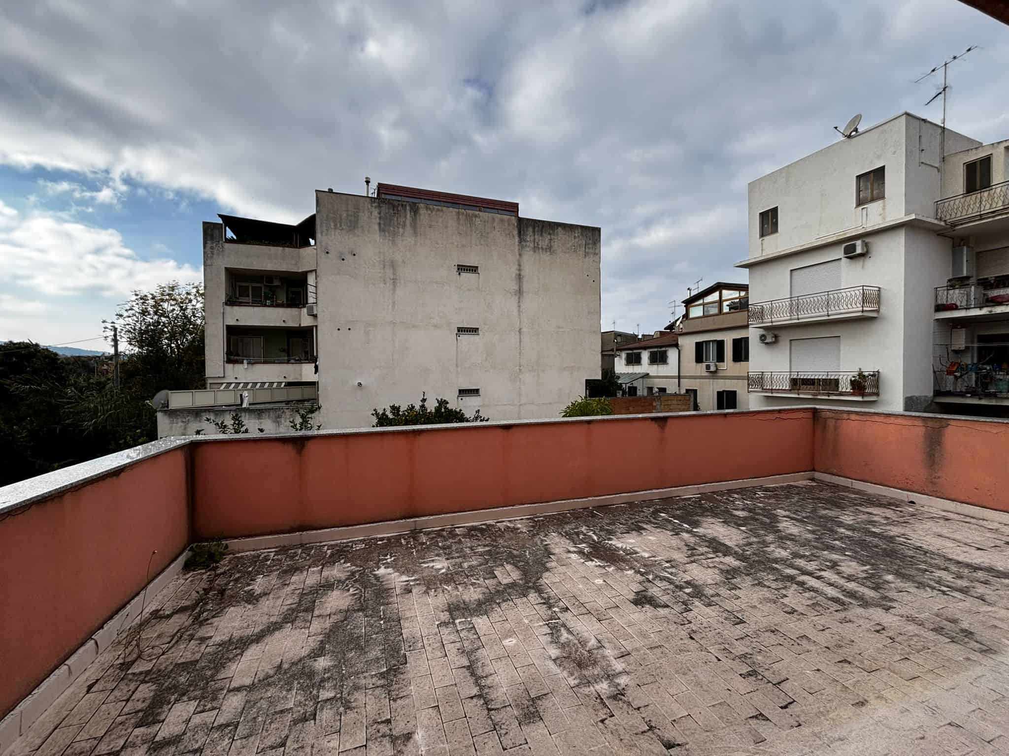 Ampio terrazzo con vista su edifici residenziali, pavimentazione in pietra, possibilità di arredamento esterno, ideale per zona relax o giardino urbano, vicino a servizi e spazi verdi.