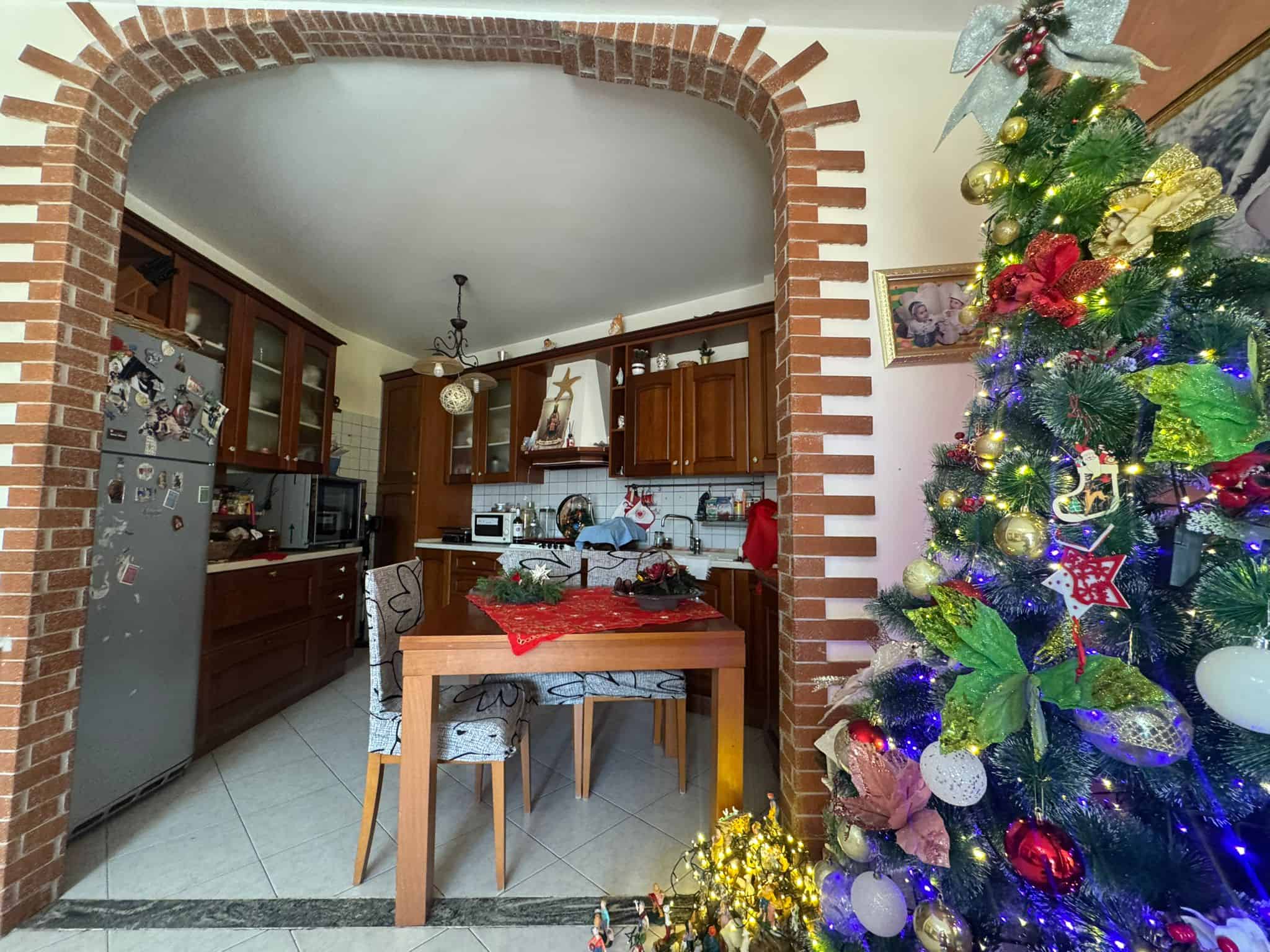 Decorazione Natalizia in Casa con Albero di Natale illuminato e cucina in stile tradizionale, ambiente caldo e accogliente, ideale per la stagione festiva, immagini di Natale, ambiente domestico, comfort e atmosfera festiva.