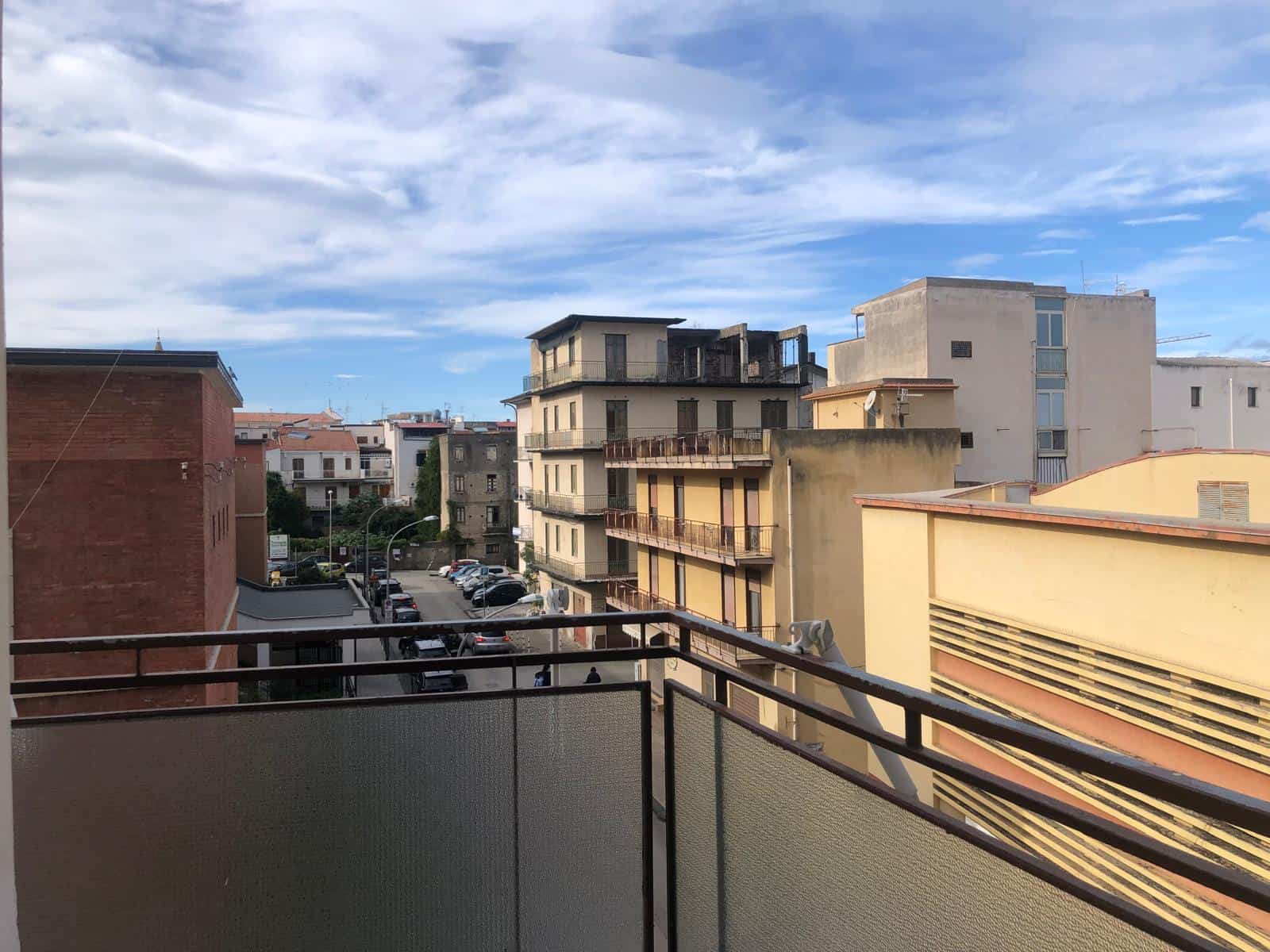 Vista panoramica di edifici residenziali nel centro di Napoli con balconi e parcheggio sotto, cielo sereno, atmosfera urbana e città vivace.
