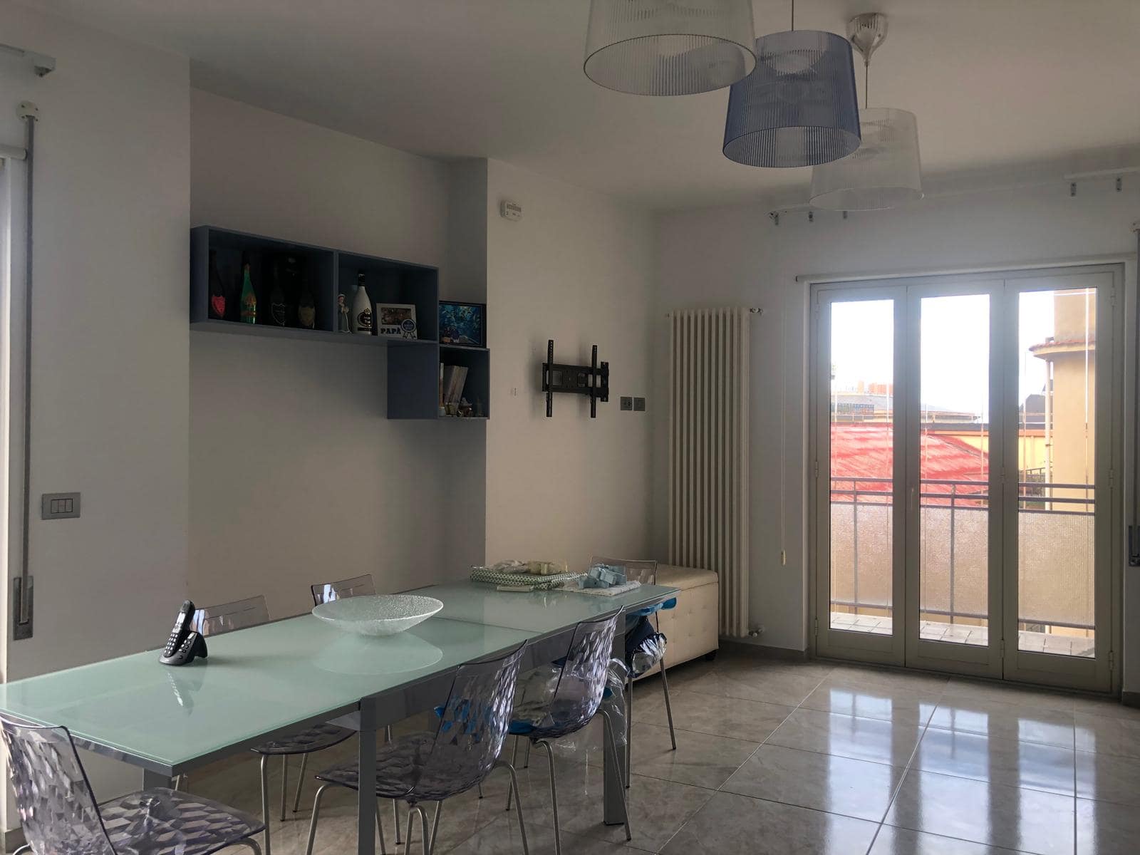 Soggiorno luminoso con grandi finestre e porta balcone, arredato con stile moderno, soffitti alte, illuminazione a soffitto e pareti bianche, ideale per vivere in ambienti accoglienti e funzionali.