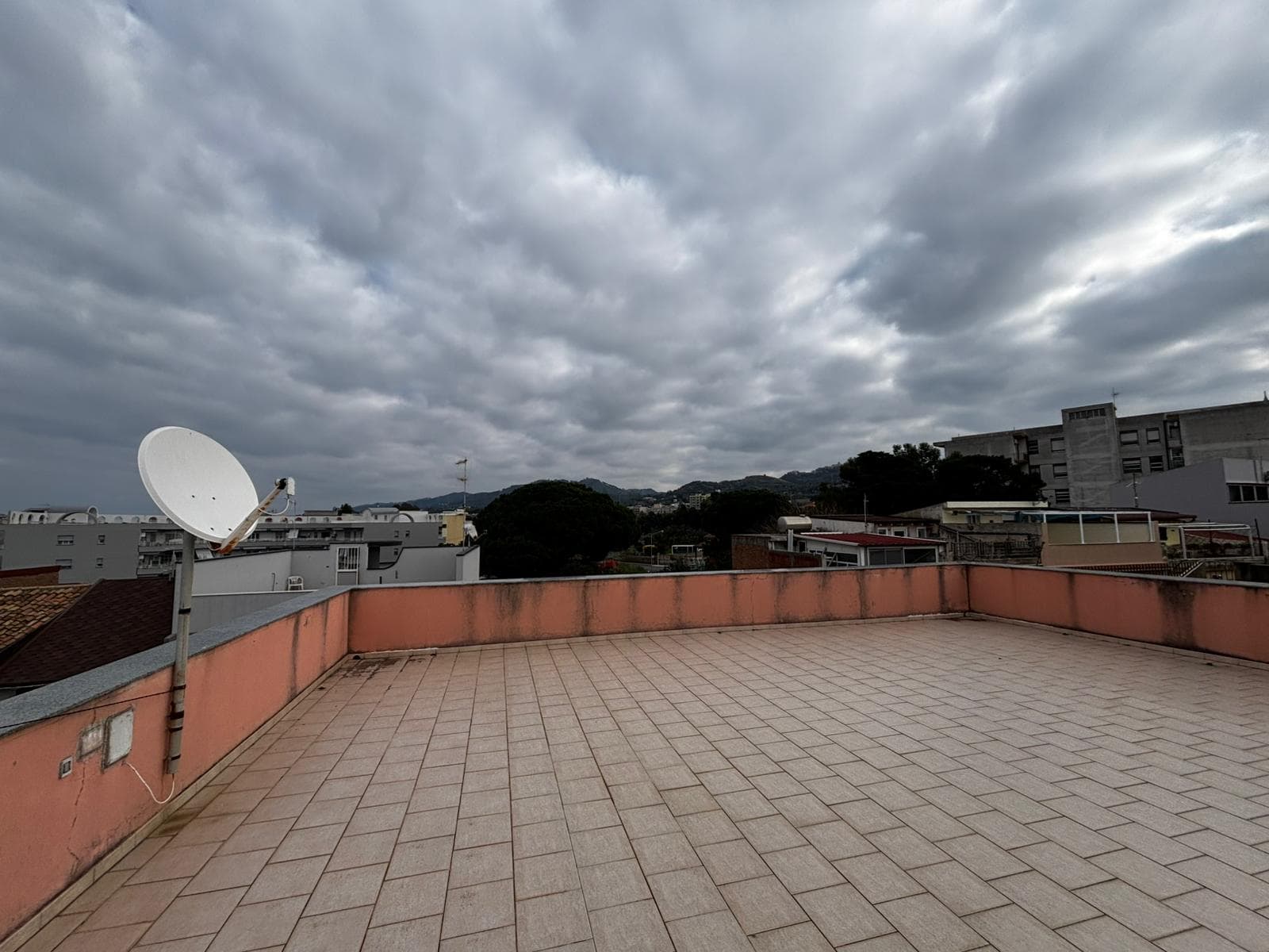 Ampio terrazzo panoramico con vista sulla città e sulle colline, ideale per relax e convivialità, con spaziosa superficie in gres porcellanato e parapetto in muratura colorato.