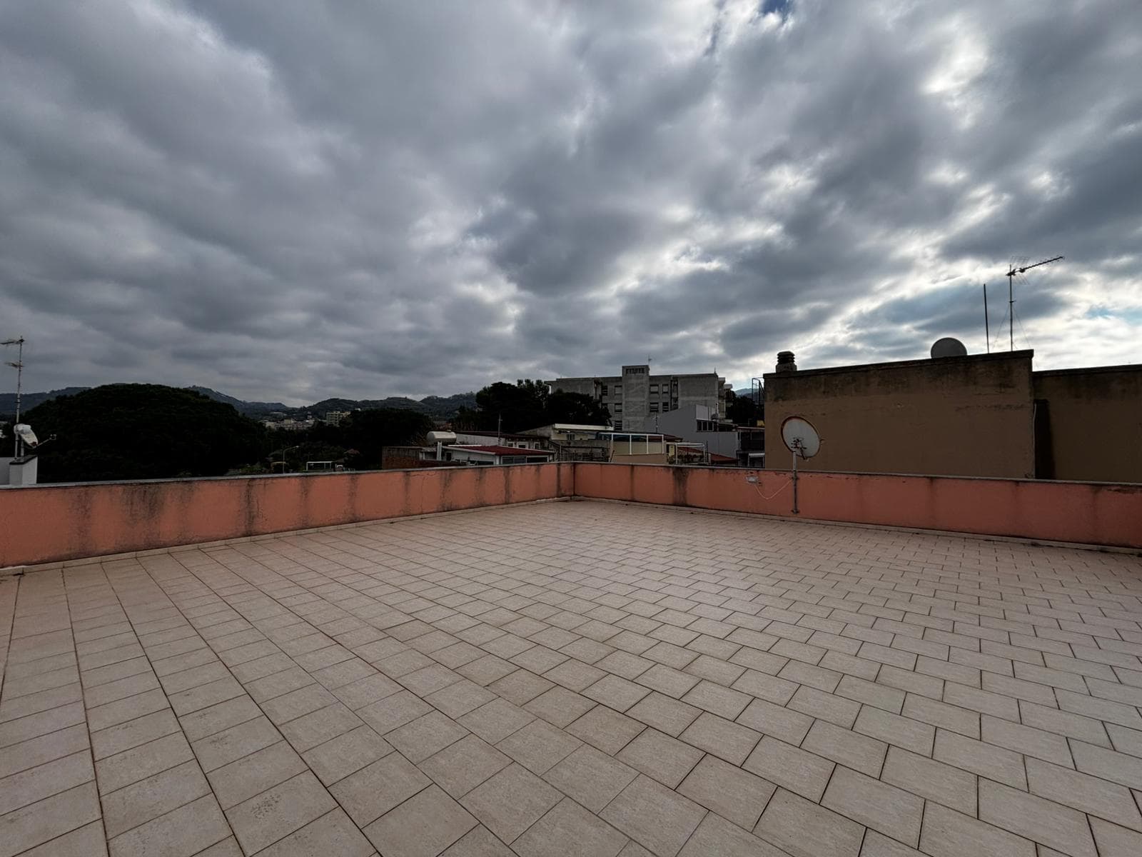 Ampio terrazzo con vista su città e colline, superficie pavimentata in gres porcellanato, ideale per spazi esterni e momenti di relax, atmosfera urbana e naturale.