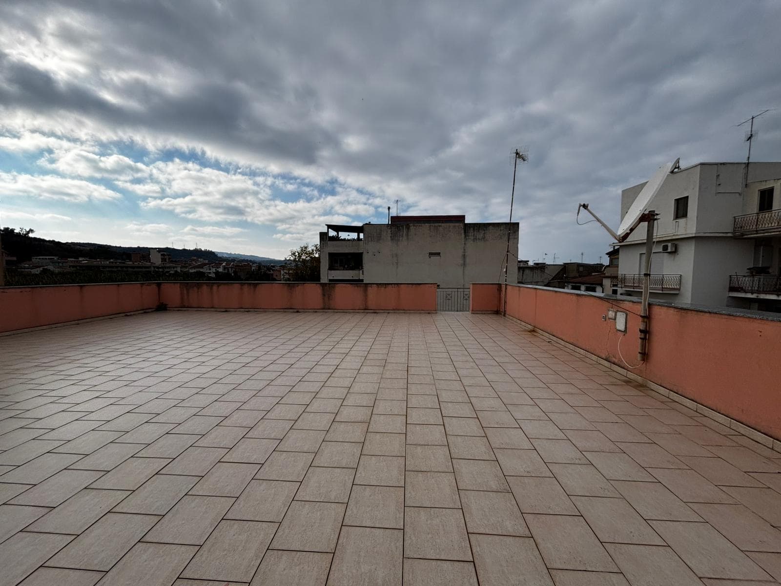Ampio terrazzo con vista sul cielo nuvoloso, ideale per relaxation e vita all'aperto, perfetto per appartamenti in zona urbana, con pavimentazione in gres porcellanato e spazio per arredi esterni.