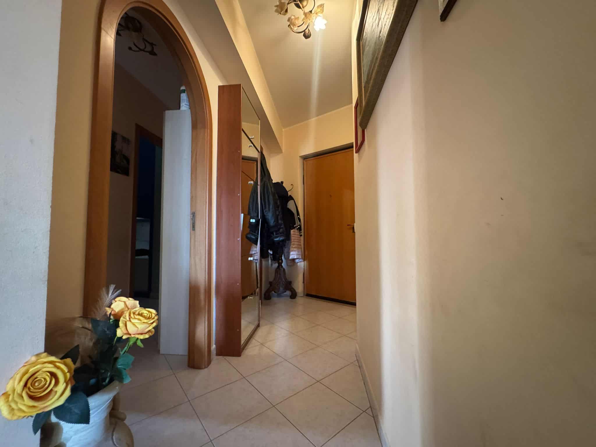 1. Corridoio di appartamento con pareti gialle, pavimento in piastrelle e arredamento funzionale, ingresso e zona disimpegno, stile classico.