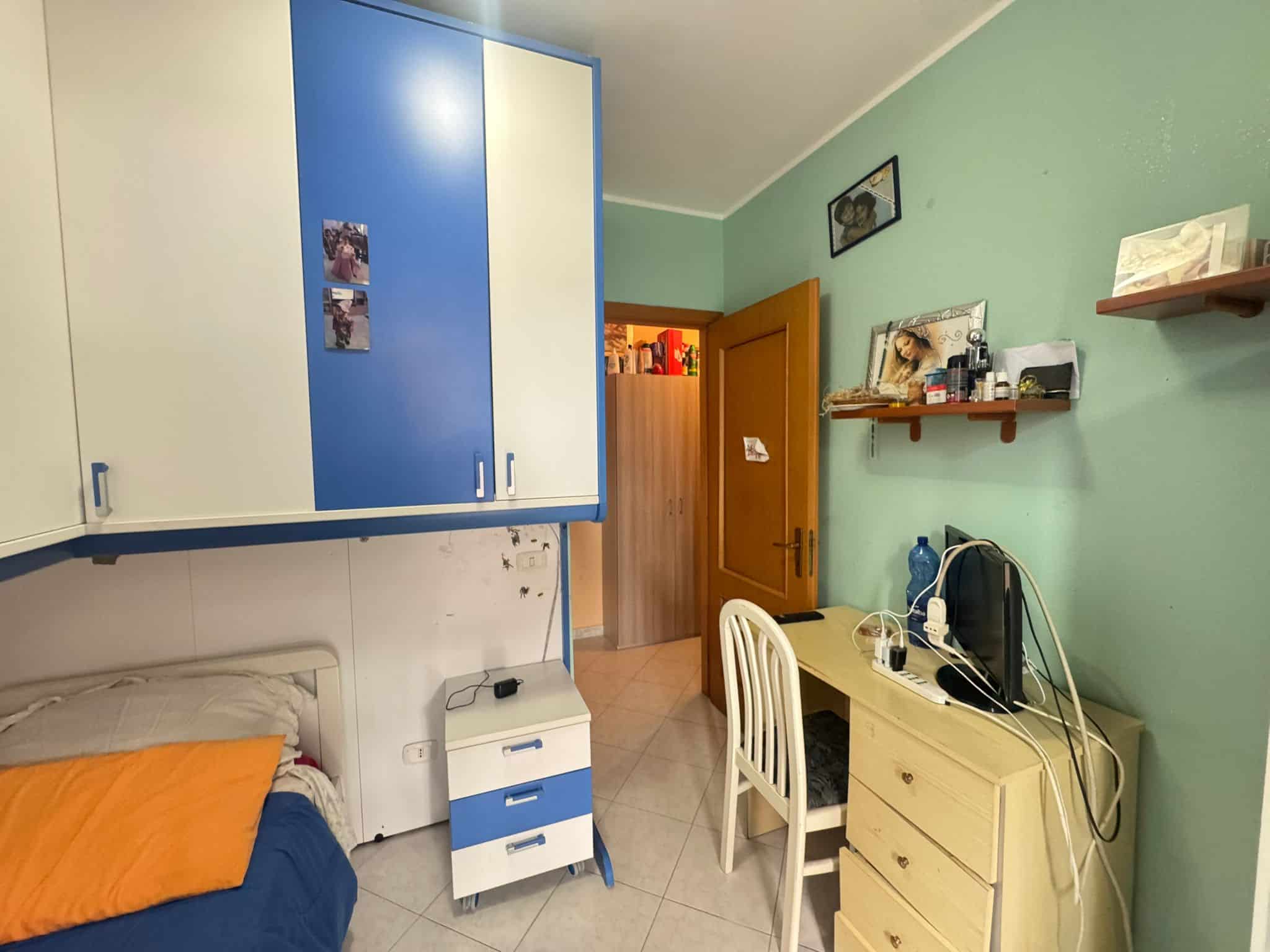 Arredamento camera singola con lettino, scrivania e armadio colorato, ambiente abitabile e funzionale, ideale per studenti o giovani.