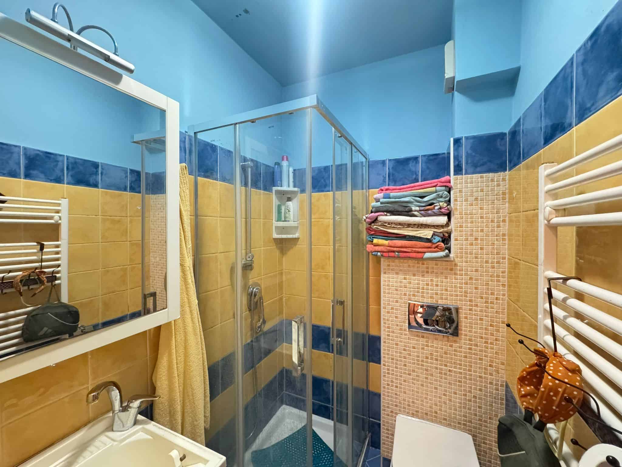 Doccia ristrutturata con pareti in piastrelle colorate in bagno accogliente e funzionale NextCasa, perfetto esempio di soluzioni di interior design per ambienti di qualità.