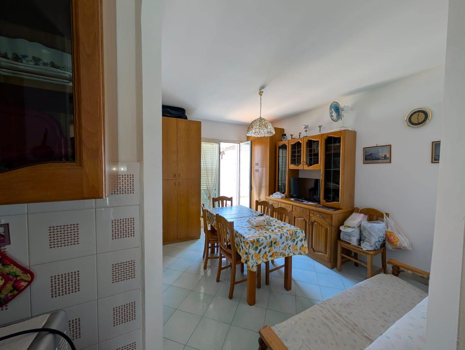 Ampio soggiorno con tavolo da pranzo, mobili in legno, televisore e balcone con luce naturale, ideale per case e appartamenti in vendita o affitto a NextCasa.