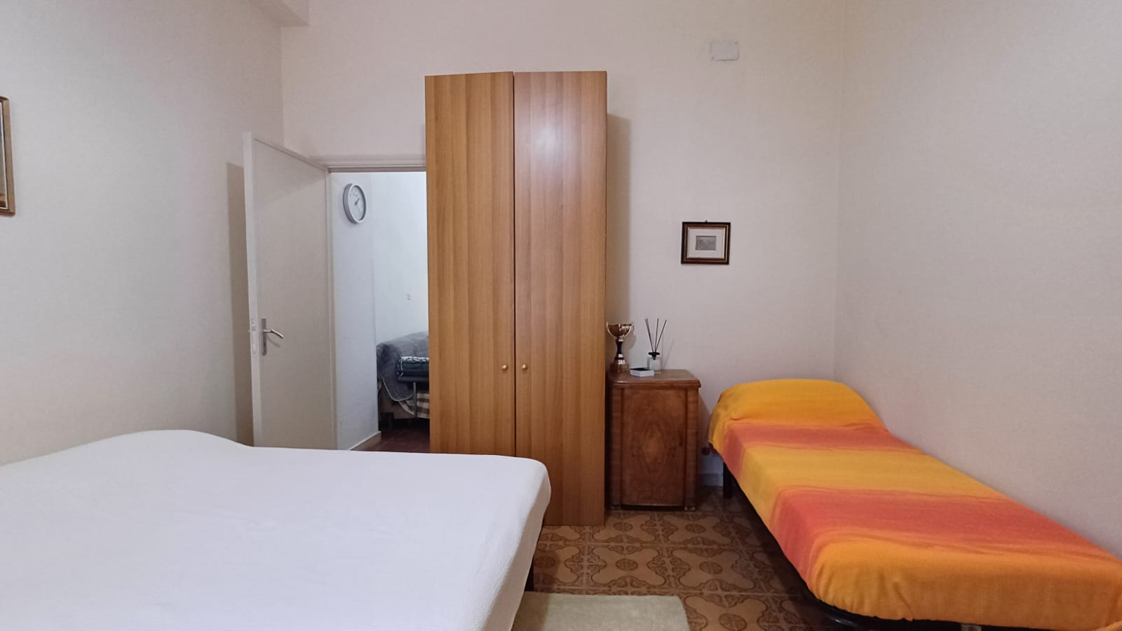 Ampio stanza con due letti singoli e armadio in legno, ambiente accogliente con decorazioni classiche, ideale per affitti brevi o lungo termine, vicino ai principali servizi.