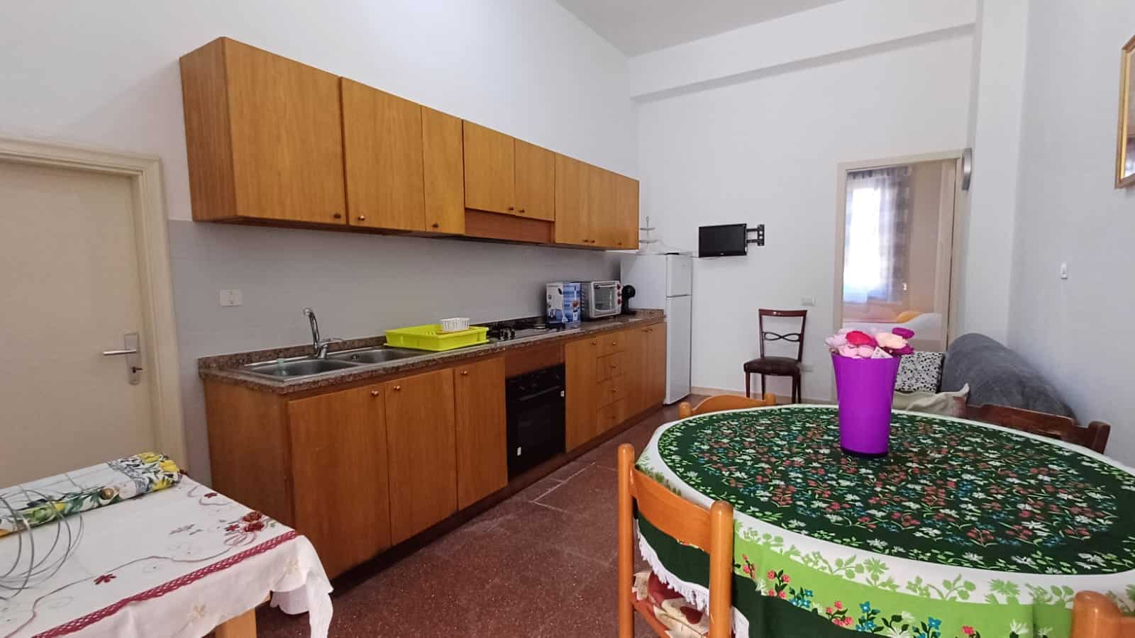1. Angolo cucina con mobili in legno, elettrodomestici e spazio pranzo con tovaglia natalizia.