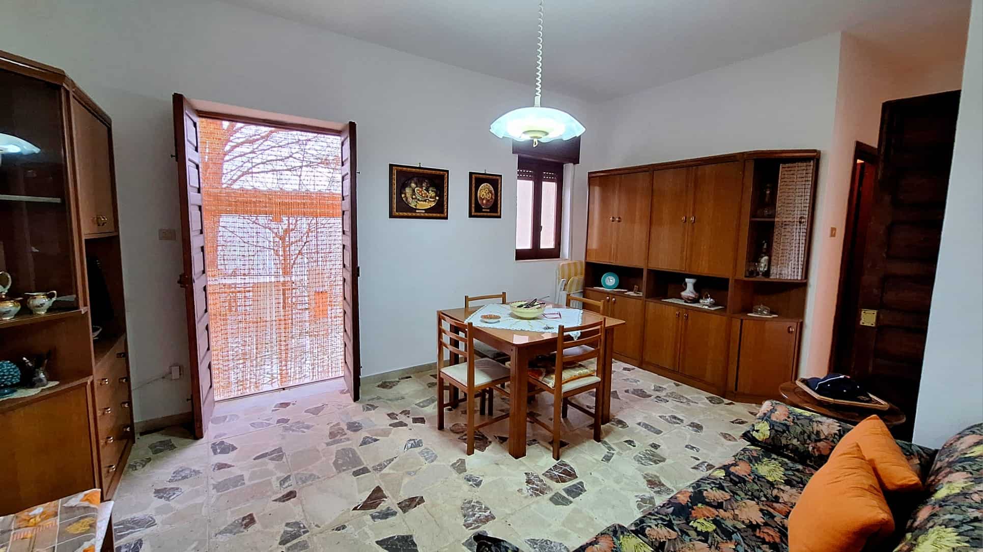 1. Appartamento in vendita NextCasa con soggiorno spazioso, mobili in legno e arredamento classico, grande finestra e porta d'ingresso in legno, ideale per famiglie.