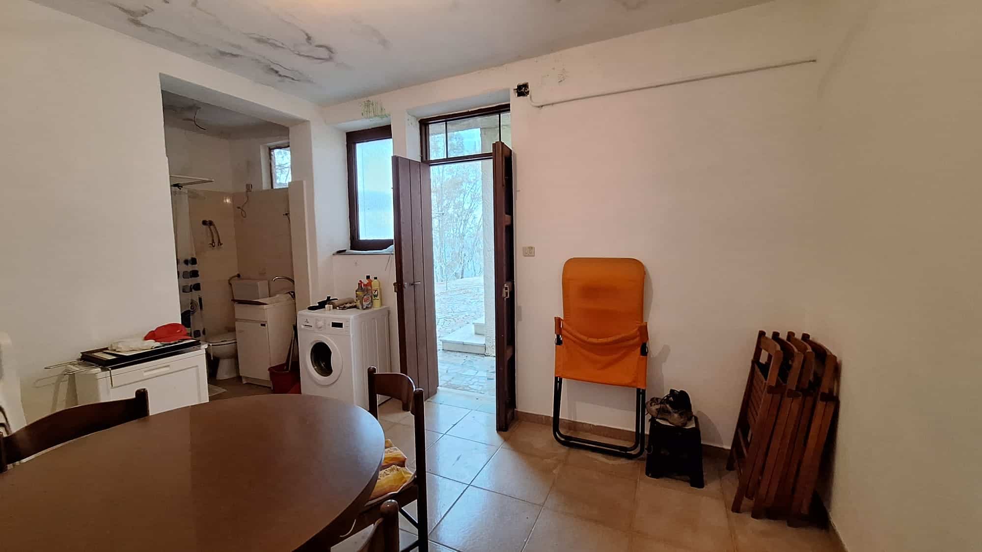 Stanza interna con ingresso, utensili, lavatrice e accessori, ambiente abitabile e funzionale per accoglienza e praticità.