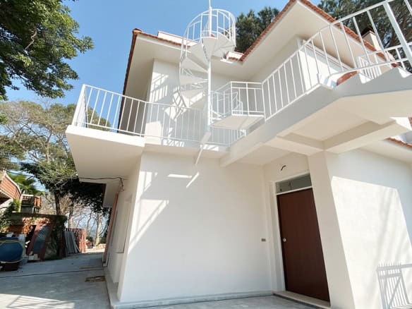 Villa moderna con terrazza panoramica e facciata bianca, ideale per residenze di lusso vicino alla natura, con spazio esterno e design contemporaneo.