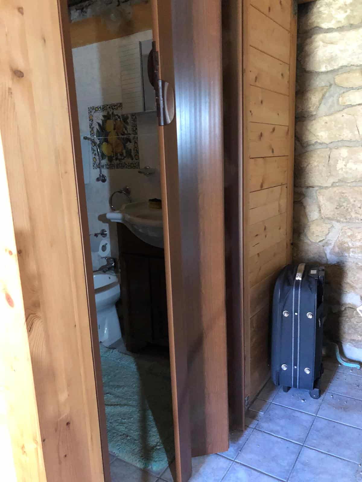 Porte in legno con bagno interno visibile, dettagli rustici e arredamento funzionale, ideale per case di montagna o case vacanza, atmosfera accogliente e autentica in stile tradizionale.