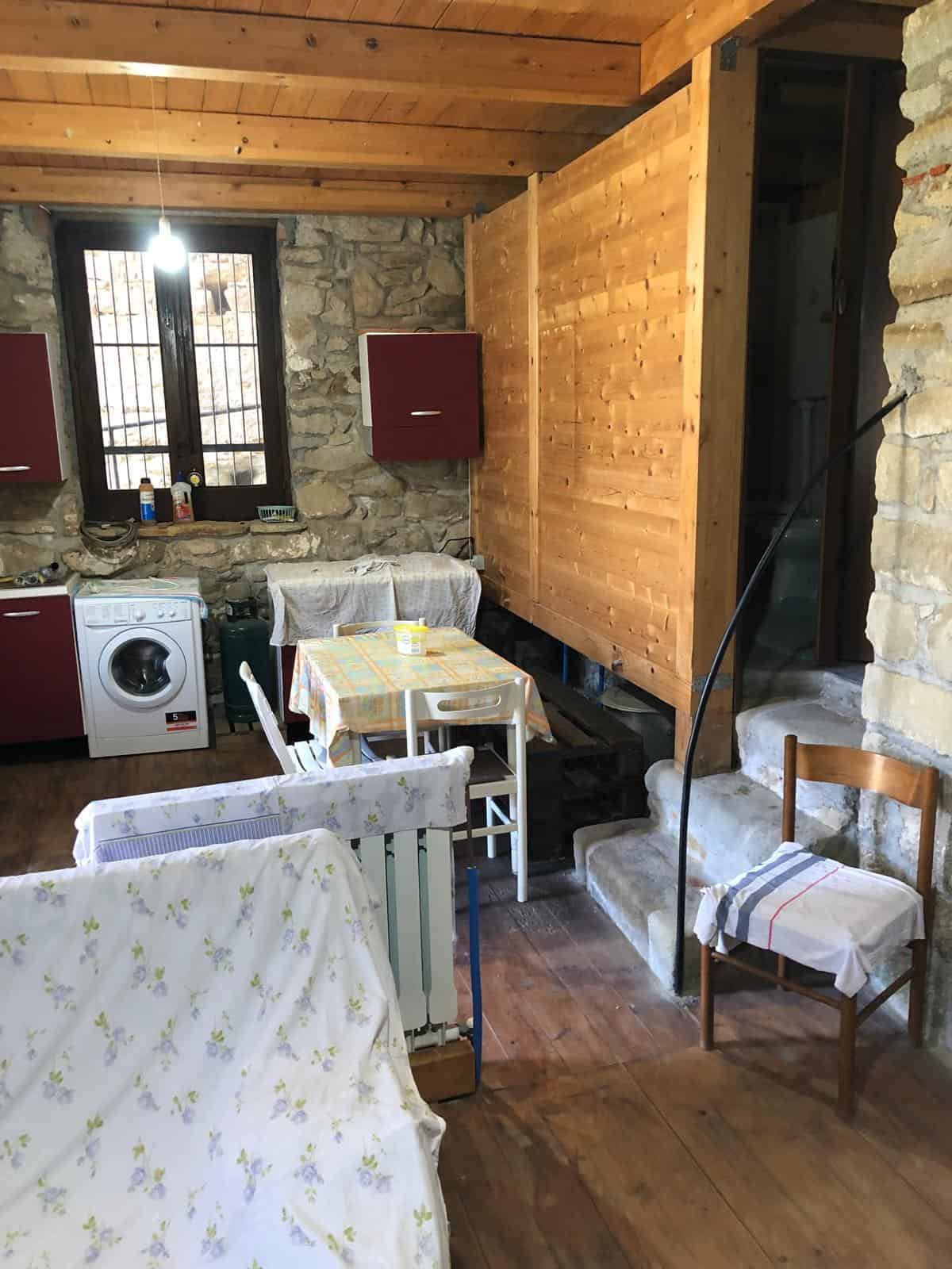 1. Interno rustico con pareti in pietra, mobili rossi e soffitto in legno, ambiente accogliente e autentico.