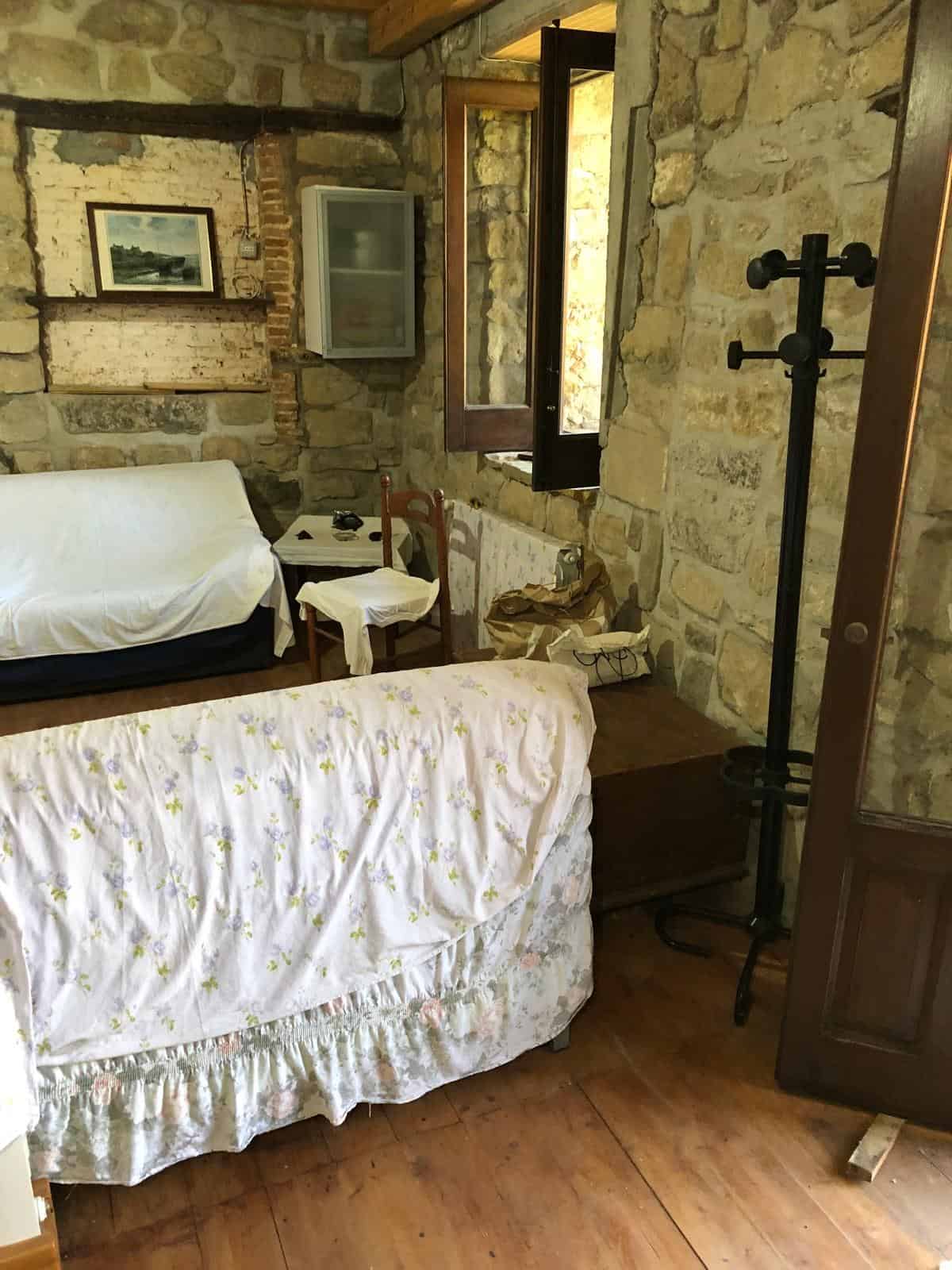 1. Ambiente rustico con pareti in pietra, divani coperti con tessuti floreali e arredi tradizionali, ideale per appartamenti in campagna o case di charme.