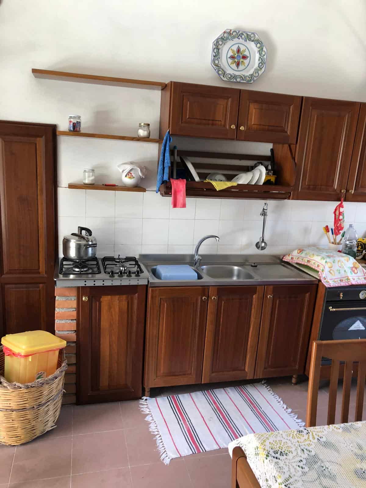 1. Cucina abitabile con mobili in legno, lavabo, piano cottura a gas e forno, dettagli pratici e funzionali.