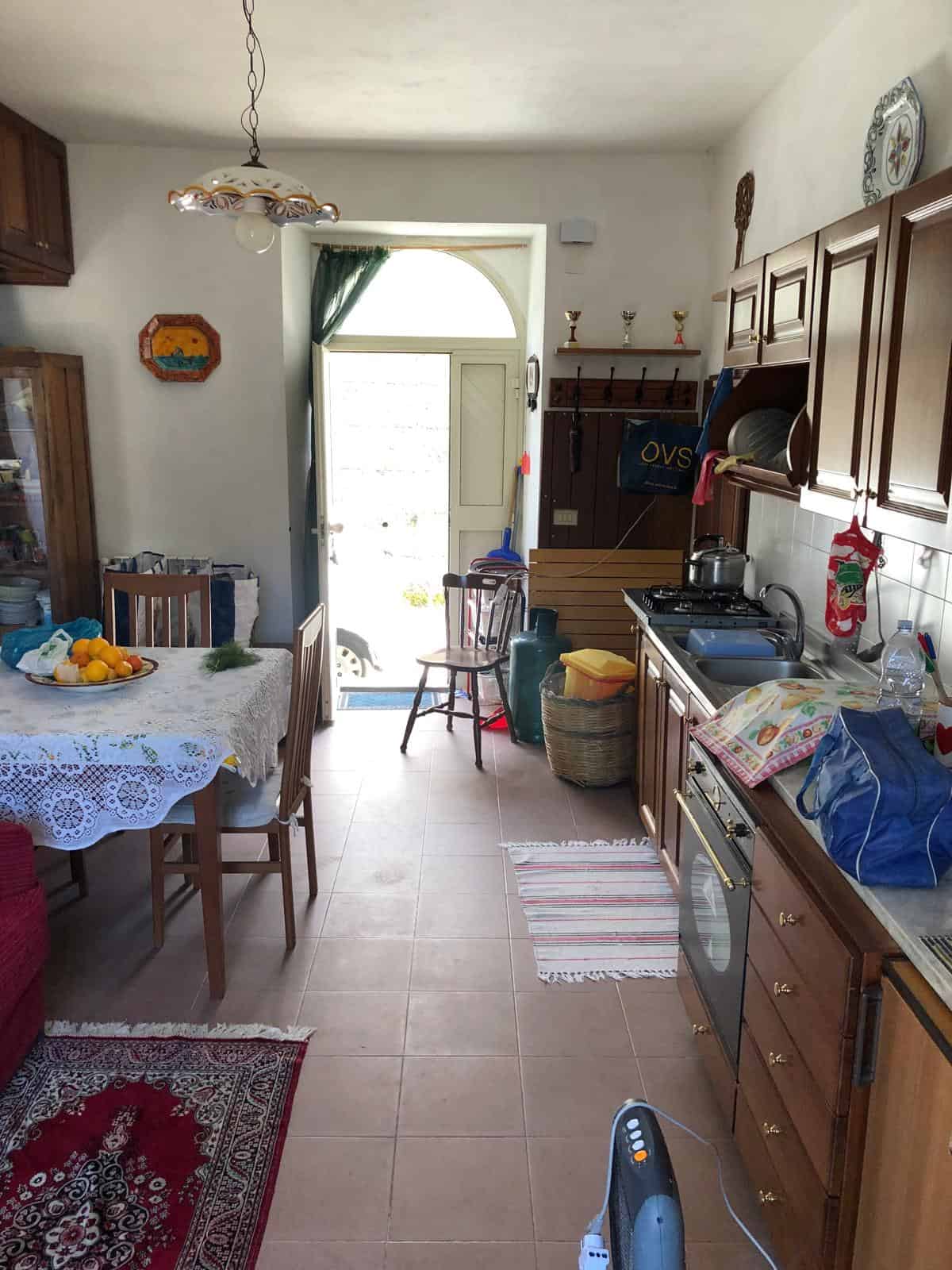 Scopri l'interno di questa cucina abitabile con mobili in legno, tavolo con tovaglia etnica, elettrodomestici e decorazioni tradizionali. Ideale per vivere e cucinare in un ambiente accogliente e funzionale.