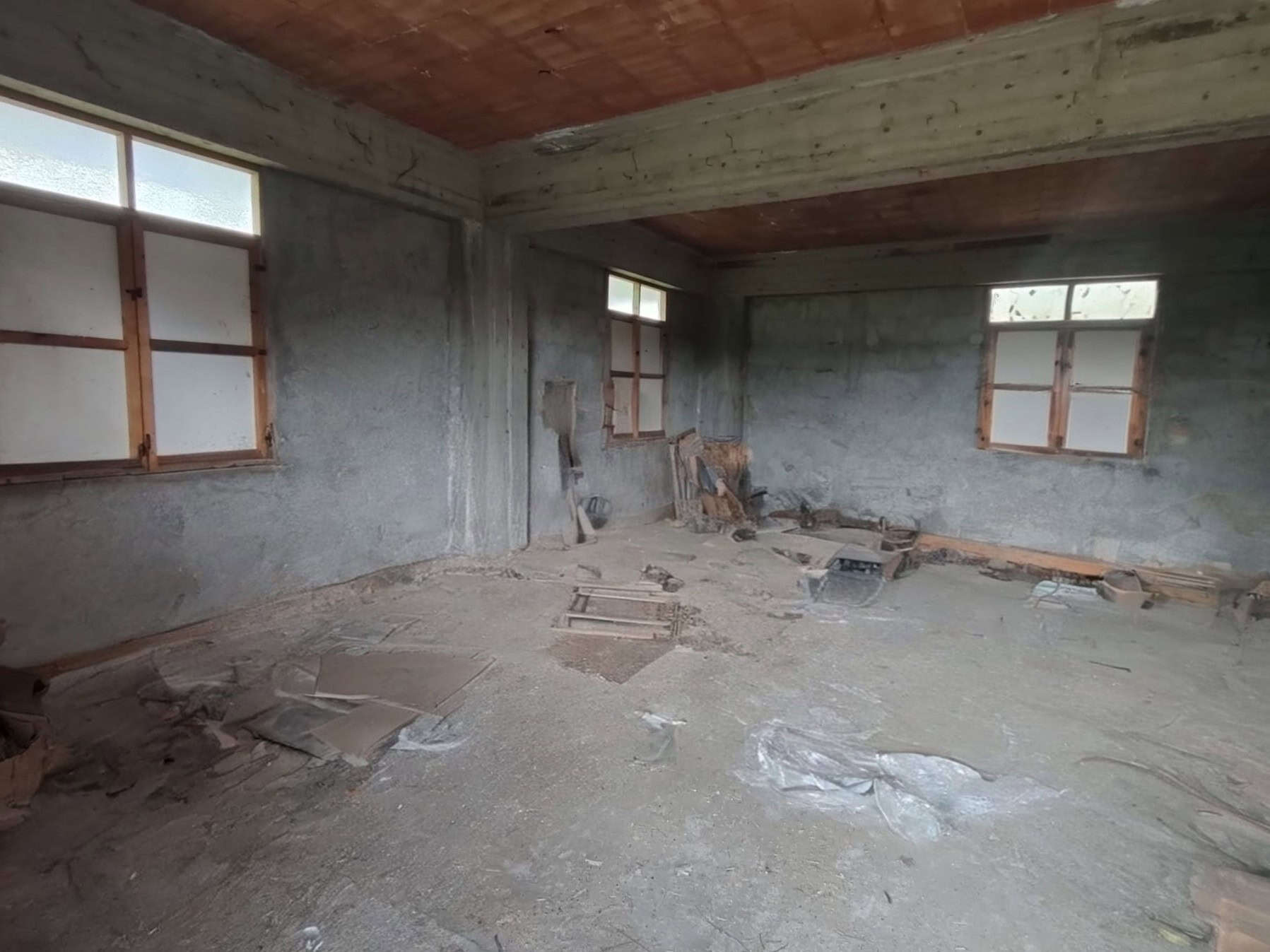 Interno di casa in costruzione, pareti in cemento e finestre con vetri opachi, pronto per ristrutturazione.